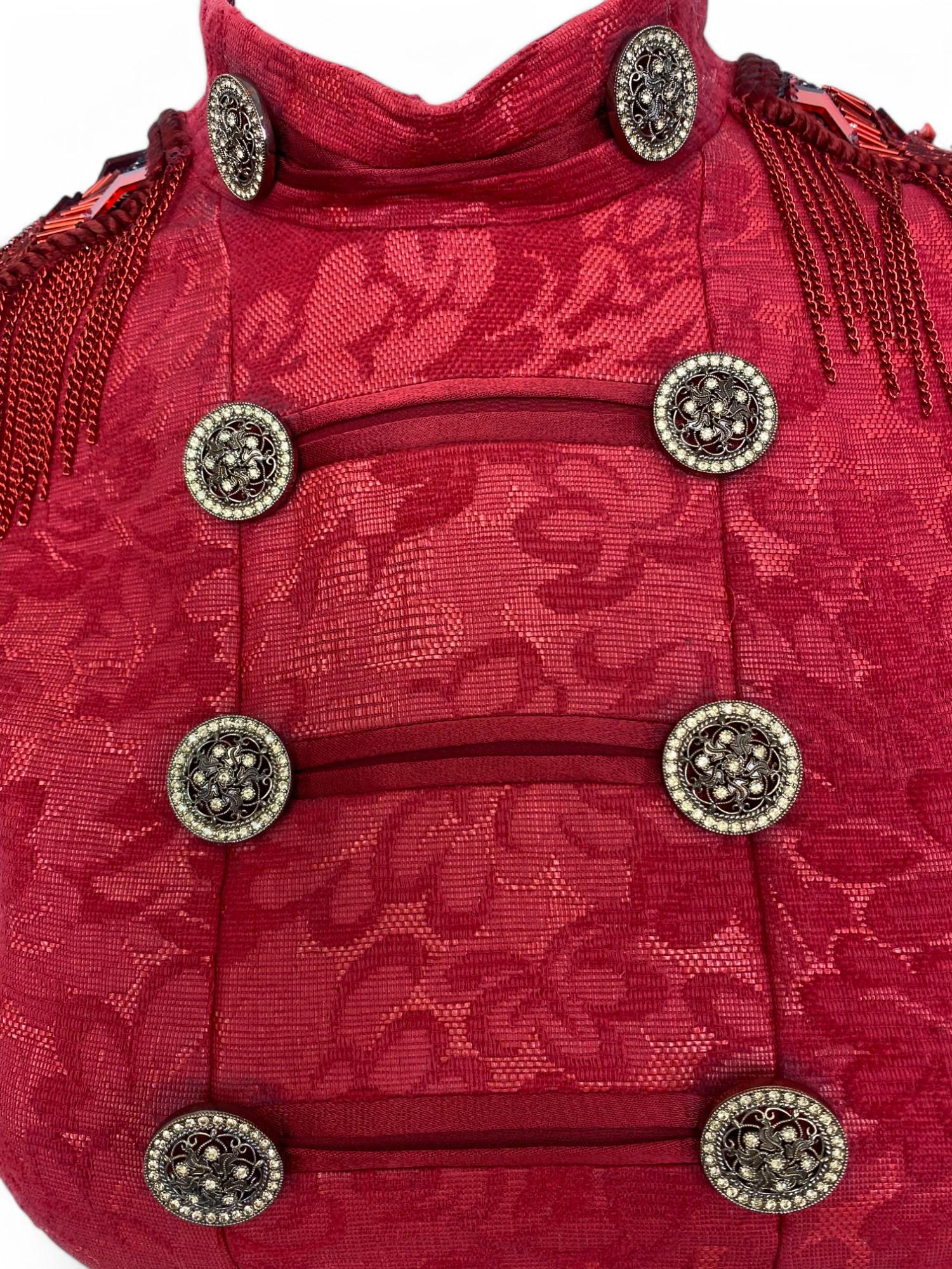 Este minivestido rojo de tapicería, una pieza inolvidable del Look 15 de la pasarela Prêt-à-Porter Otoño 2014 de Versace, es una imponente fusión de opulencia y filo militar. Confeccionado en un rico jacquard texturizado con una silueta atrevida, el