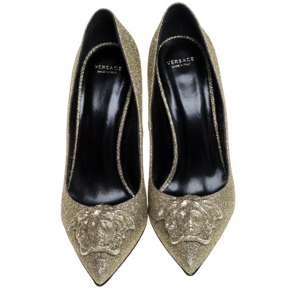 Be ready for constant attention and admirable gasps from your audience when you walk in these pumps from Versace. Crafted from gold glitter fabric, they carry pointed toes with the iconic Medusa logo embellished on them and 10 cm stiletto heels. The