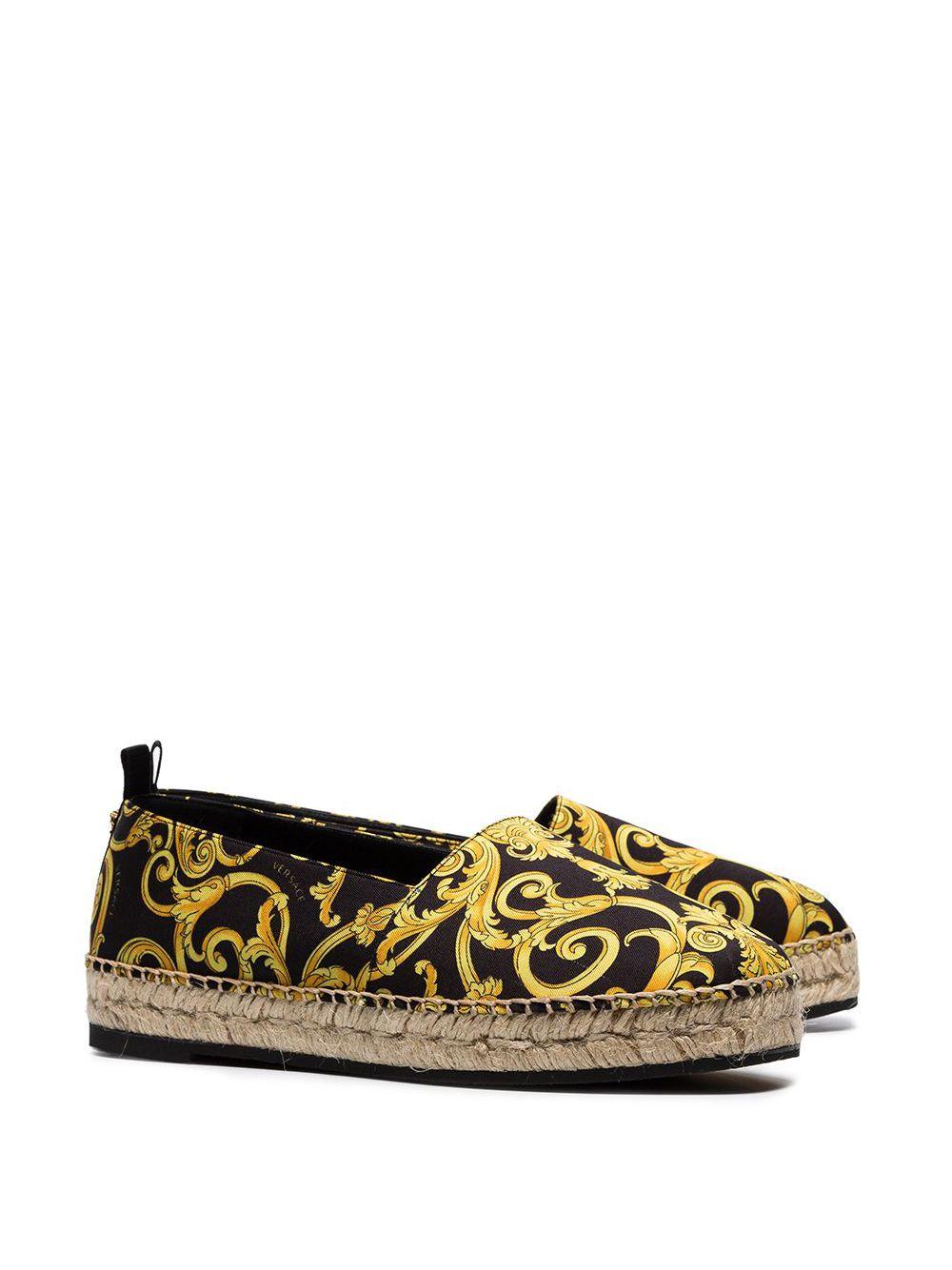 Versace Gold Hibiscus Barocco Espadrille Shoes w/ Braided Raffia Detail

Donatella pays tribute to her late brother Gianni Versace by bringing his original designs back to the forefront of the label. Archival prints, iconic motifs and retro-inspired