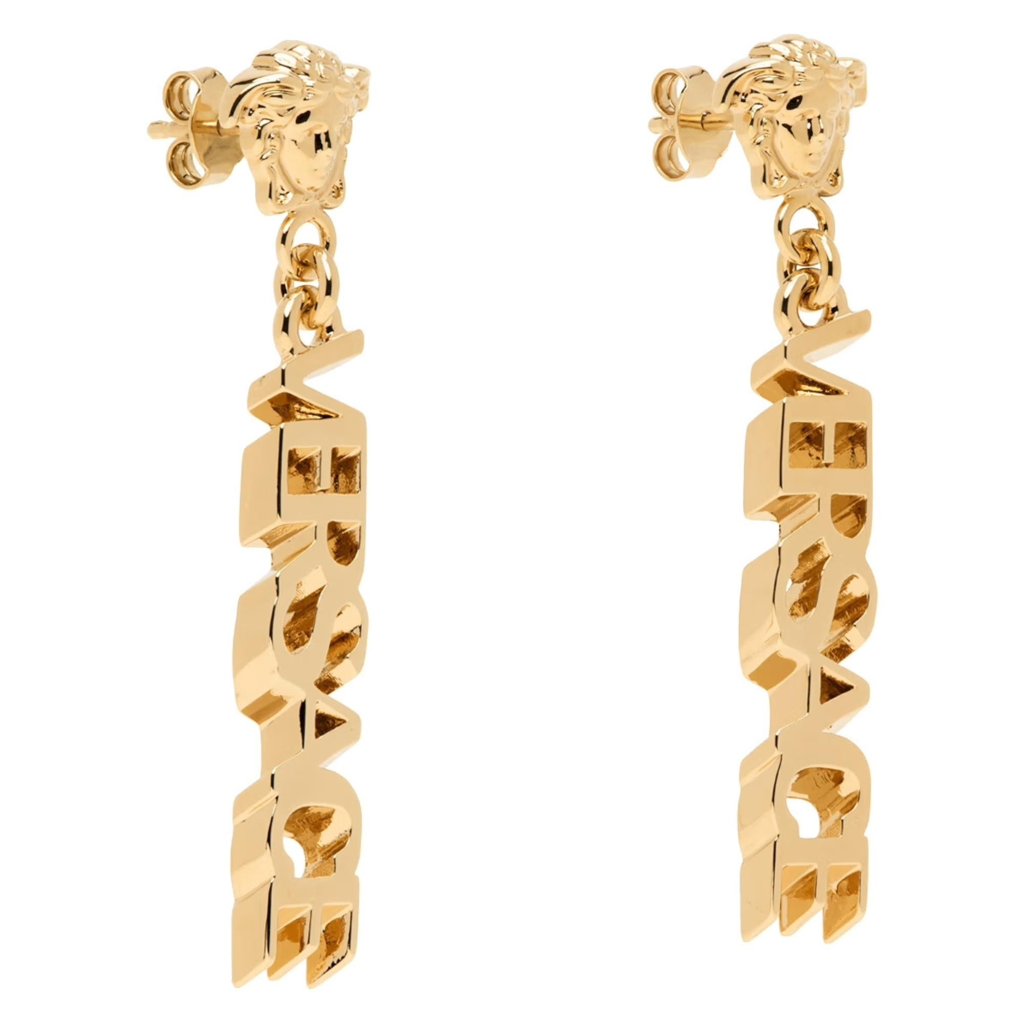 Pair of drop earrings in gold tone brass. 

· Signature Medusa at face
· Logo at drop
· Post-stud fastening
·  Versace gold tone color
· Drop 2