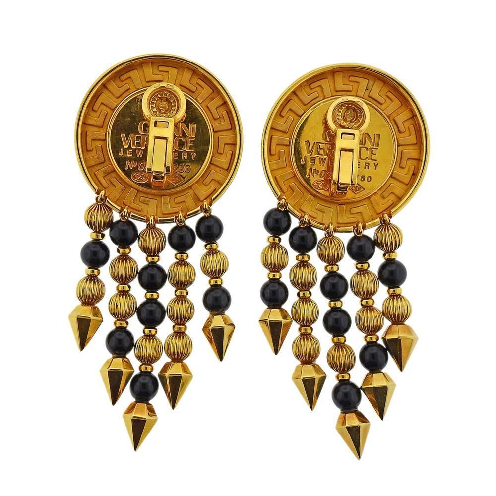 Pair of limited edition large 18k yellow gold drop earrings by Versace, depicting signature medusa , with gold and onyx drop beads. Earrings are 76mm x 34mm. Marked: Gianni Versace Jewellery, No. 002 18k 750. Weight - 61.2 grams.E-03051
