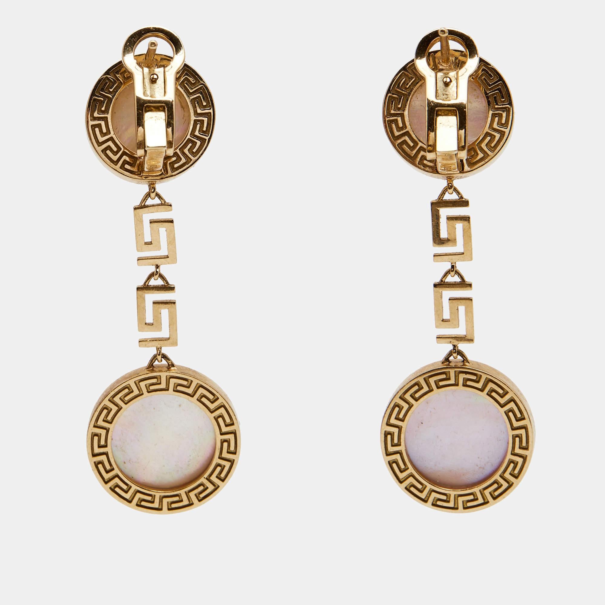 This Versace pair of earrings is a splendid piece of jewelry that you'll find easy to pair, whether with a party/evening outfit or an effortless fall wedding edit. Made of 18k yellow gold, the earrings carry two circular charms set with mother of