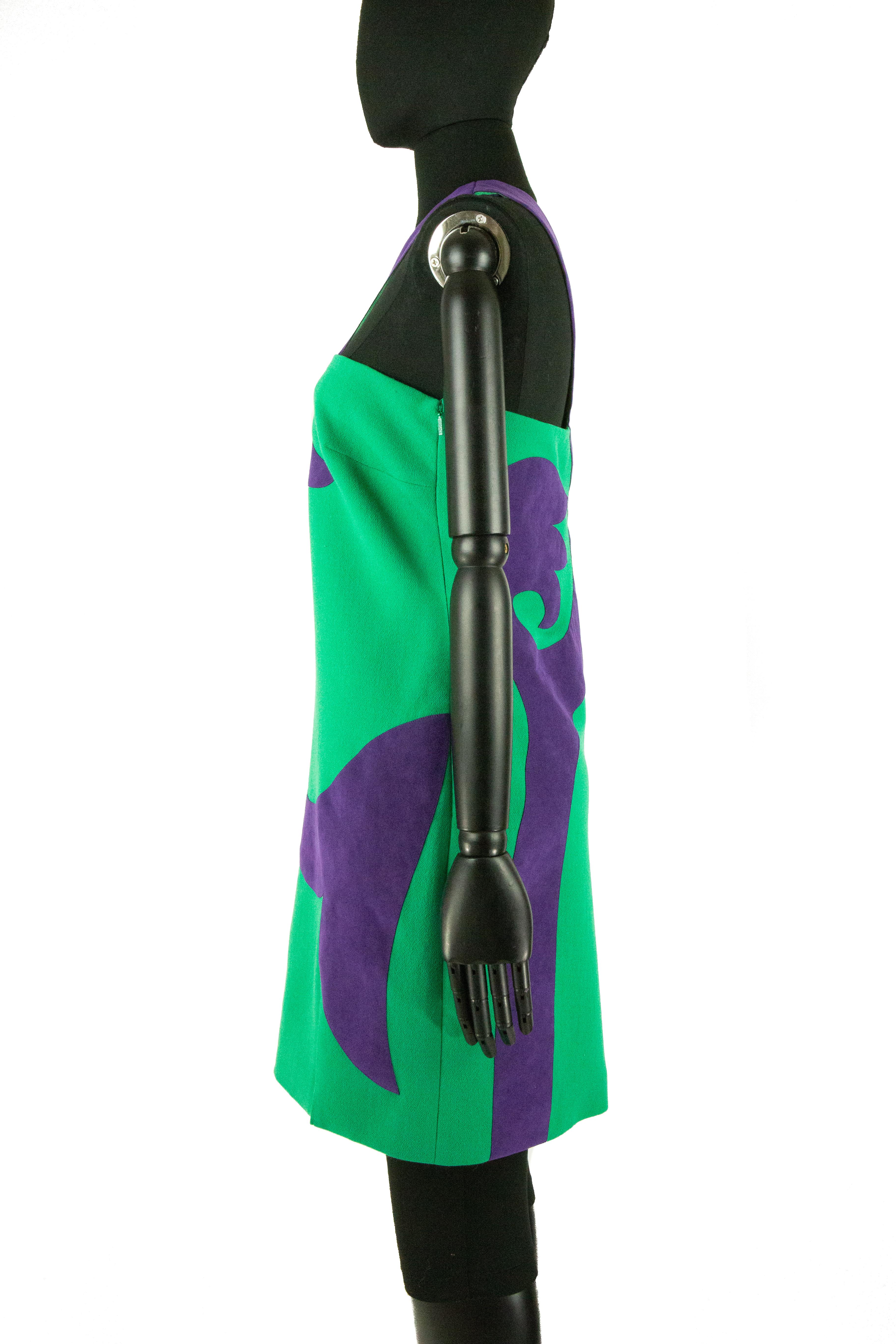 A contemporary Versace minidress in green with a swirled purple motif in purple suede. The motif then grows into the asymmetrical one shoulder. The dress also has a short thigh slit, finished with an invisible side zipper.