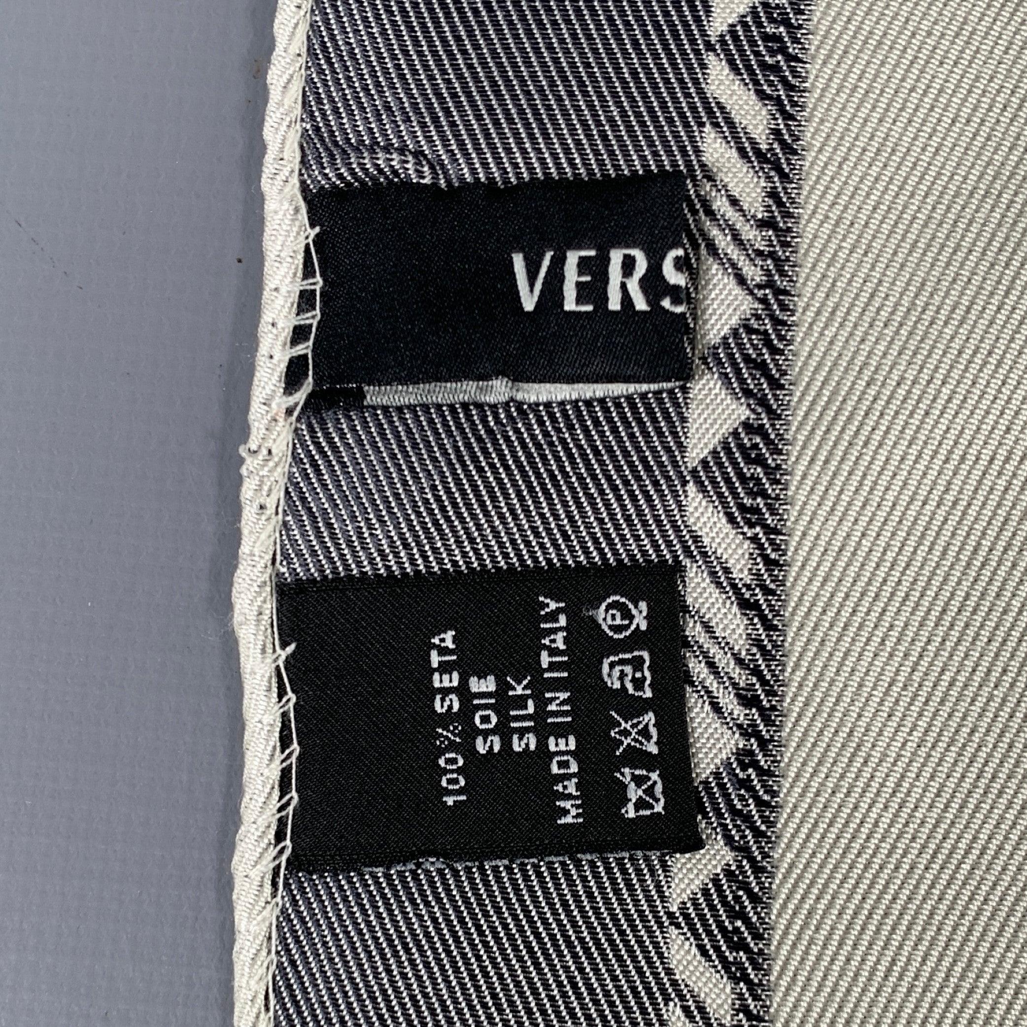 Versace è un fazzoletto da taschino in seta grigia e crema con un motivo jacquard geometrico a blocchi di colore e un bordo a cornice. Made in Italy.Ottime condizioni di usato. Lievi segni di usura. 

Misure: 
  13 pollici  x 13 pollici  
  
  
