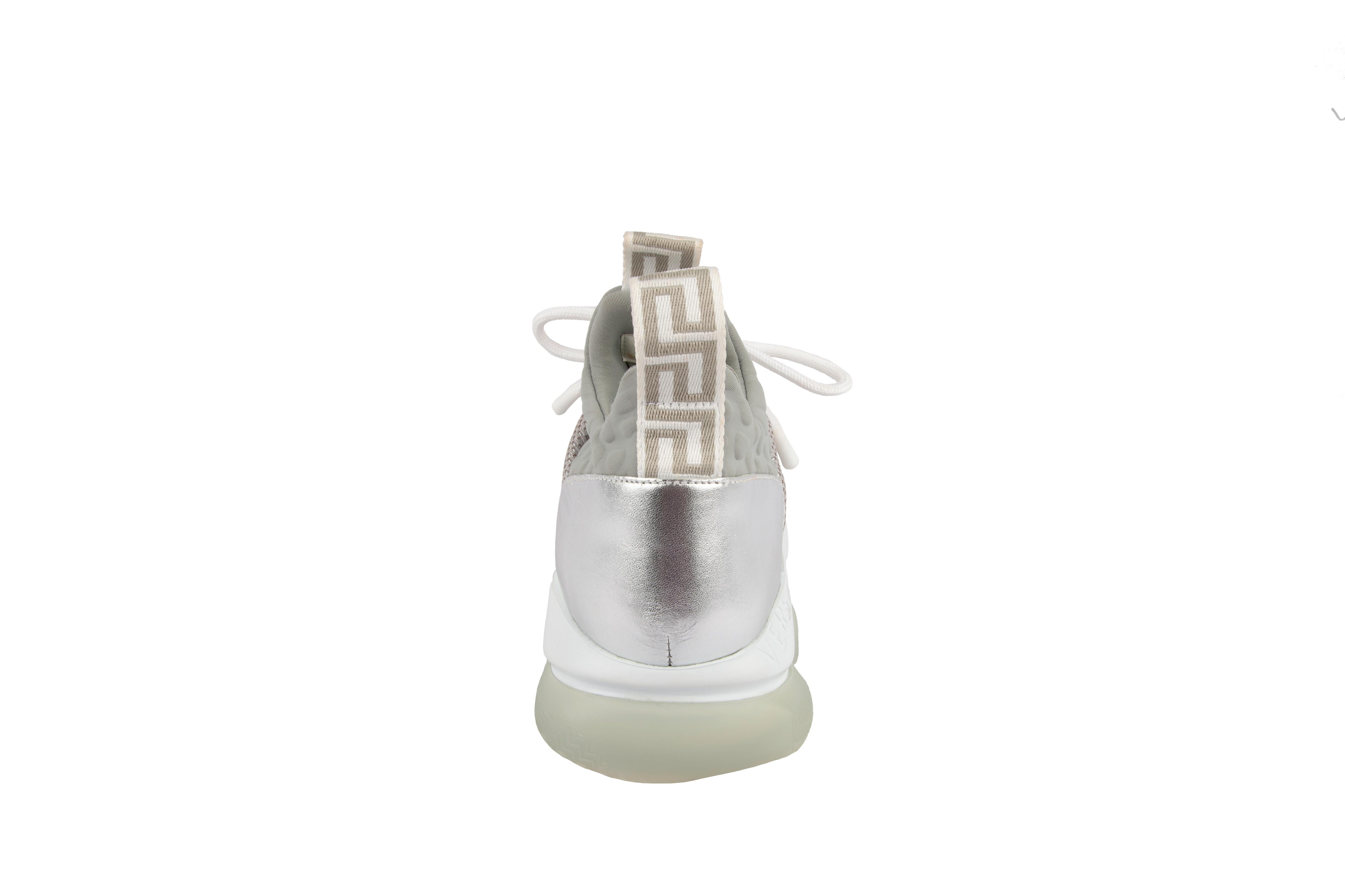 These Versace Cross Chainer silver sneakers feature puff-croc neoprene accents on the tongue and lining, a translucent glitter toe cap, and the defining chain link outsole. Versace’s Greca key pattern is stamped onto both pull tabs for branding,