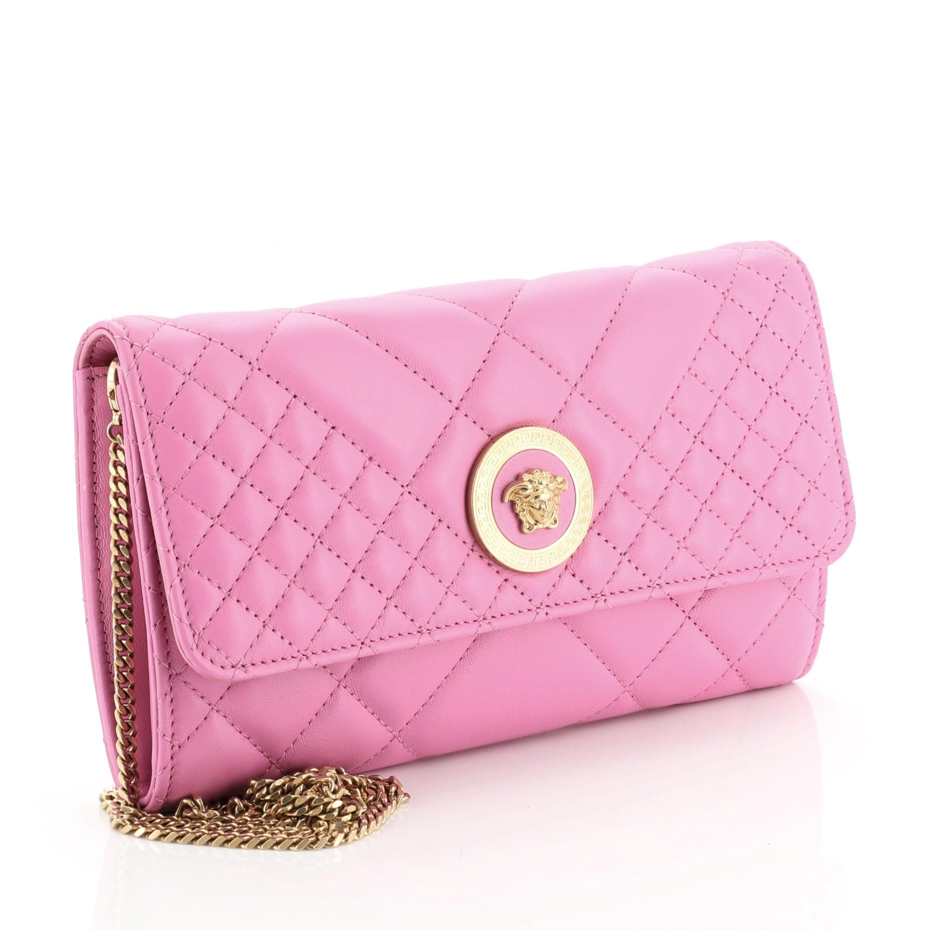 This Versace Icon Wallet on Chain Quilted Leather, crafted in pink quilted leather, features a chain shoulder strap, flap top with Medusa head medallion and gold-tone hardware. Its snap closure opens to a pink leather interior with multiple card