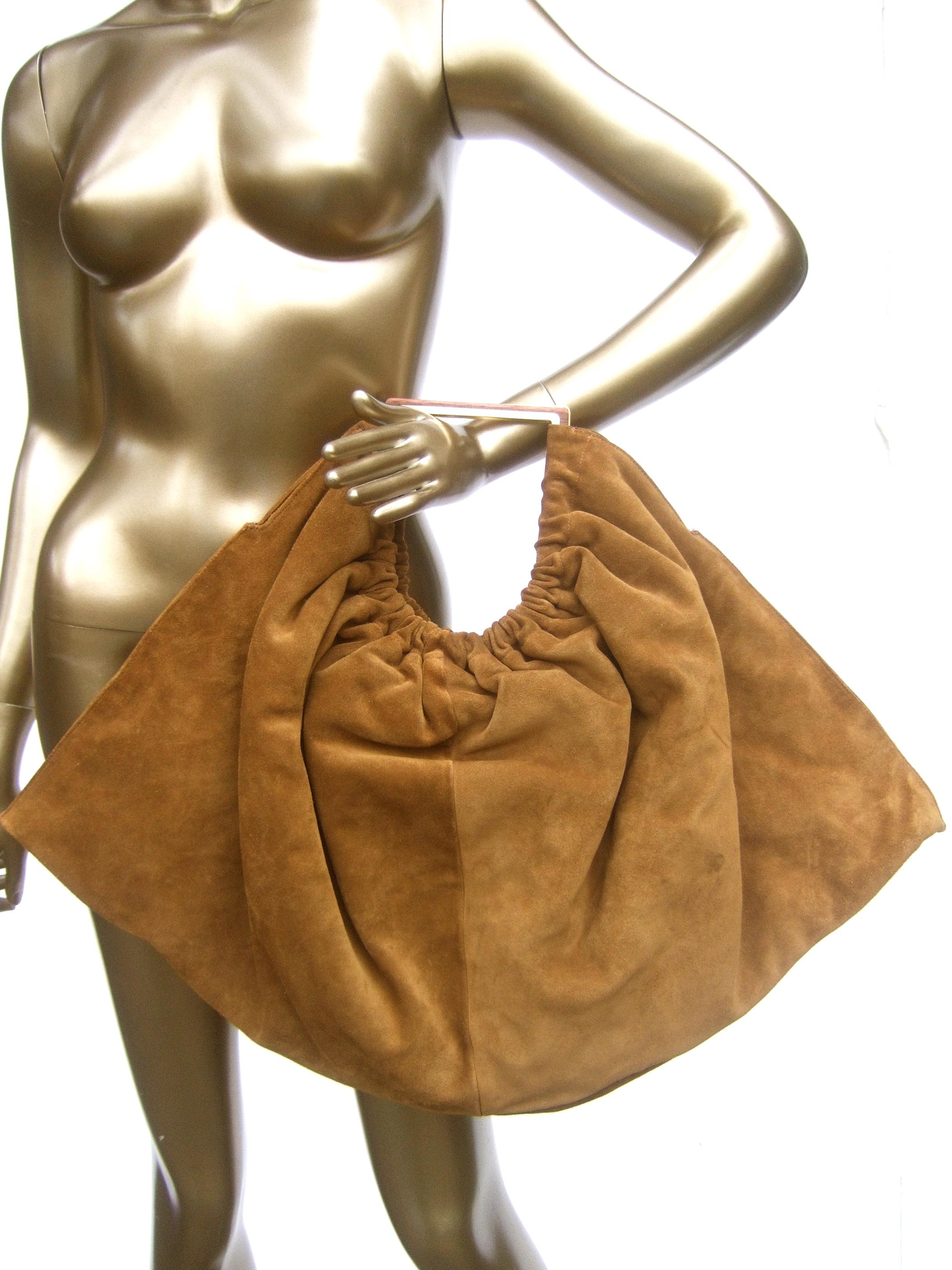 Versace Italian brown suede large scale handbag c 1990s 
The stylish handbag is covered with luxurious caramel 
color brown suede

The handle is designed with sleek polished gilt metal combined
with a band of natural wood. The interior is lined in