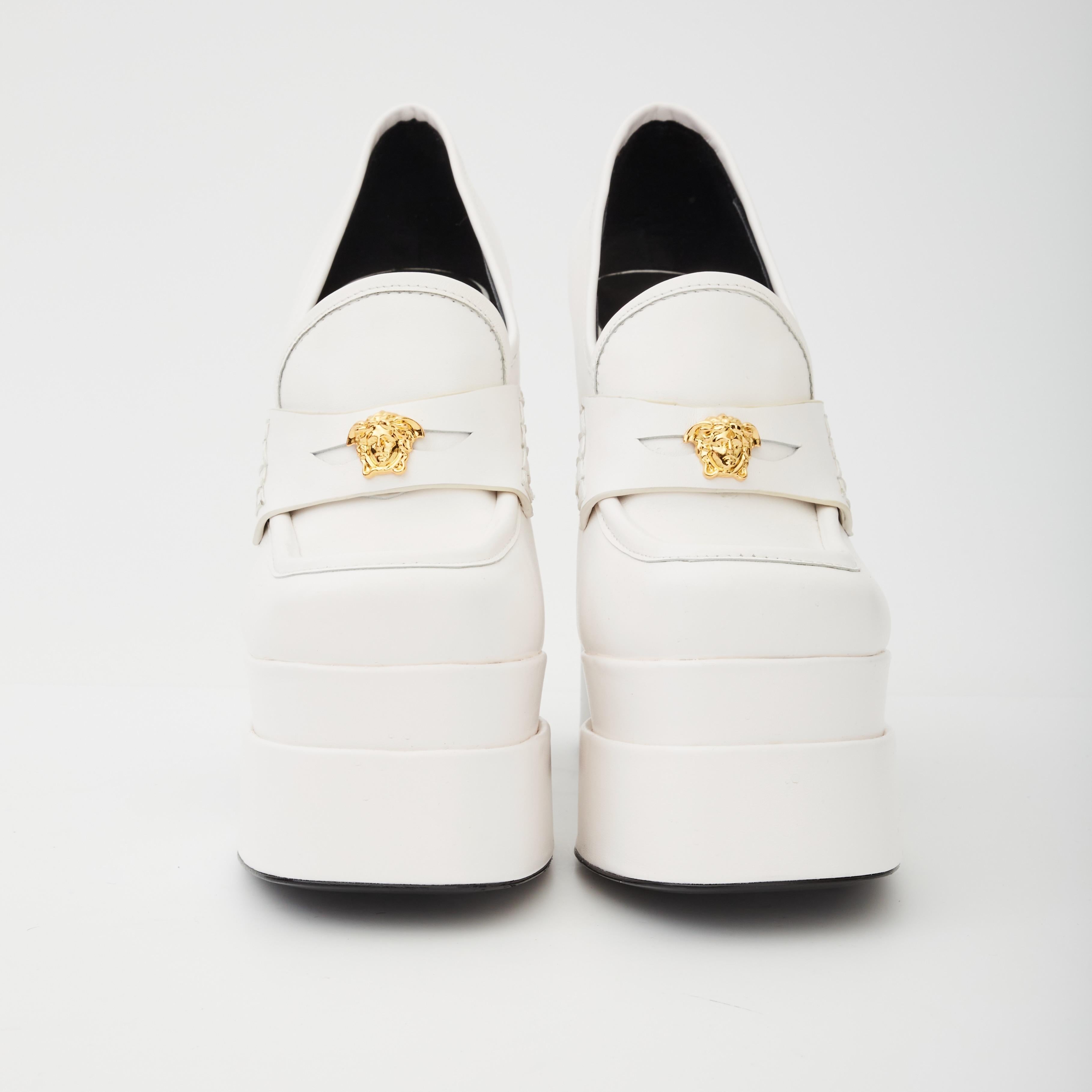 These Versace's Juno platform pumps feature a chunky silhouette, gold-tone Medusa plaque details, a leather composition, a platform sole, square toes and a white. color.

COLOR: White
MATERIAL: Leather
SIZE: 38 EU / 7 US
HEEL HEIGHT: 155 mm /