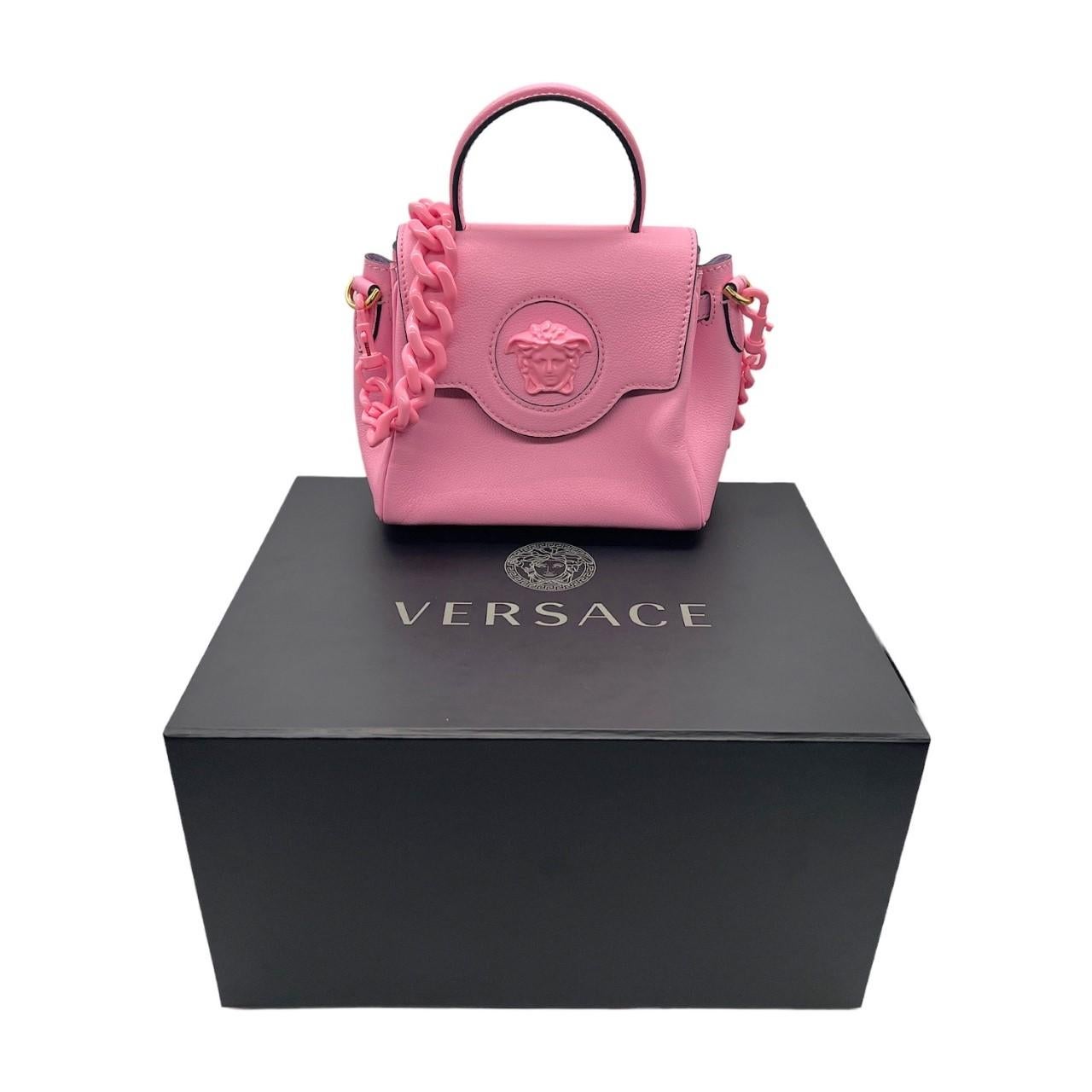We are offering this beautiful Versace handbag. Crafted in Italy, made with pink leather and gold-tone hardware. It features the classic Versace Medusa head and a removeable chain shoulder strap in pink. It has a top handle with a magnetic fold-over
