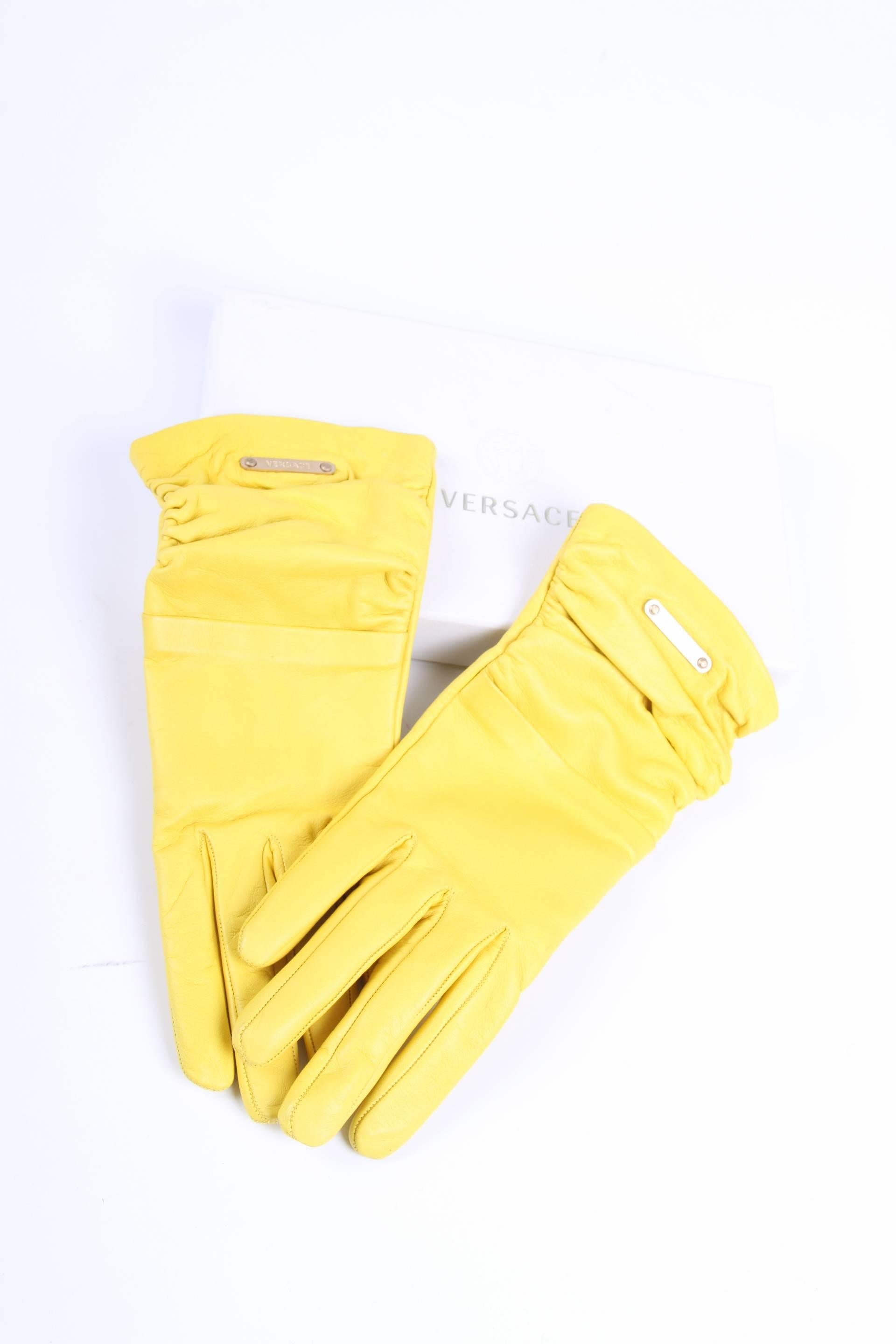 Outstanding pair of gloves by Versace crafted in bright yellow leather.

Embellished with pleats and a light gold-tone plaque with Versace logo. Lining in 100% silk in a beige color.

New! Comes with little box.

Size: S

Made in Italy.