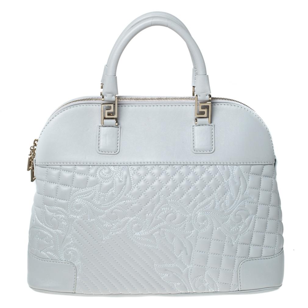 Versace brings you this glamorous bag to make you outshine everyone else and receive never ending compliments! The light grey bag is crafted from leather and styled with a quilted floral design on the exterior. It flaunts a gold-tone tassel accent