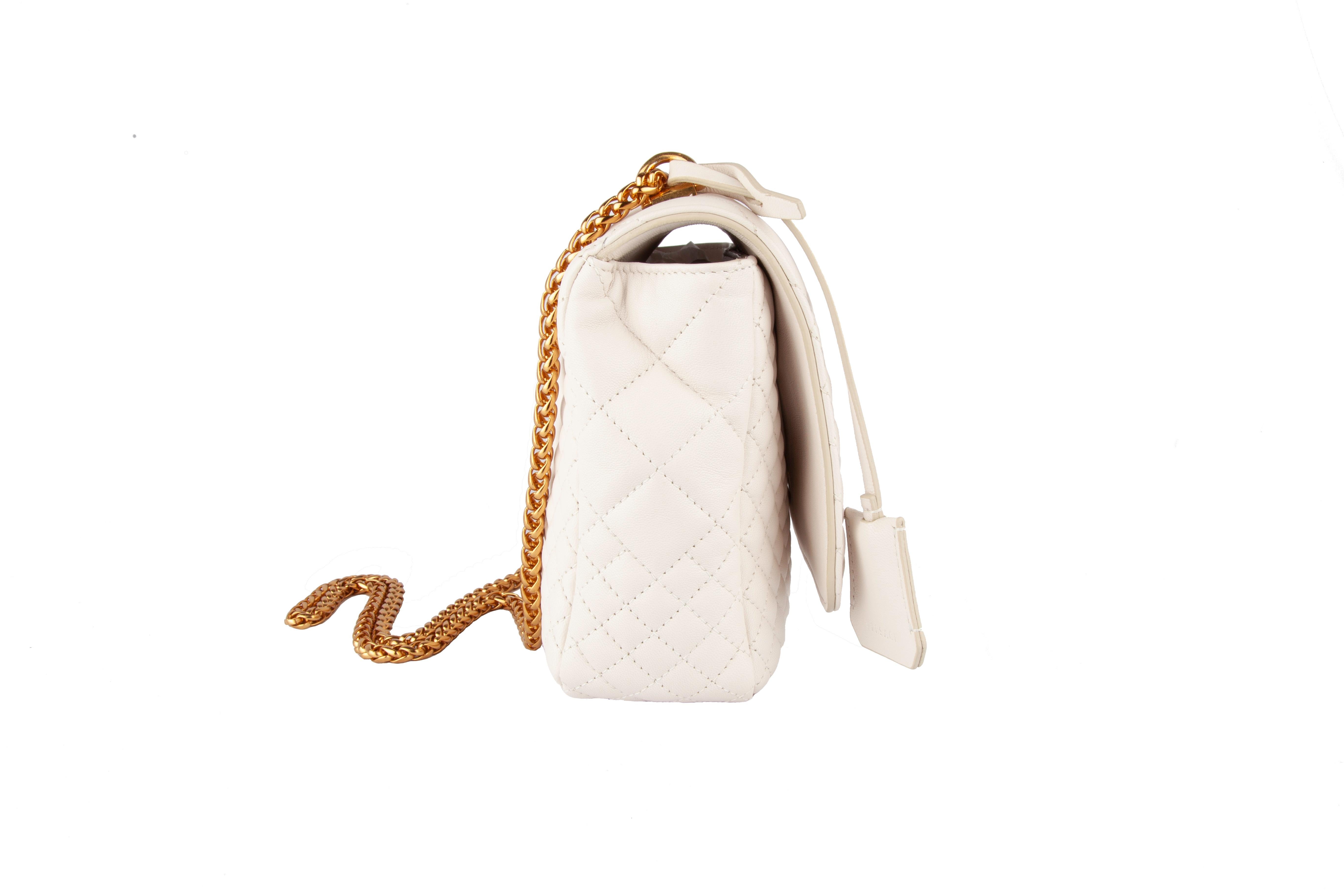 This medium white quilted leather Versace Icon Shoulder Bag features two medusa details, a gold tone chain strap, a fold-over closure, a hanging key fob, and a logo embossed lock. Brand new. Made in Italy.

Measurements: Approx.  10 x 4 x 7