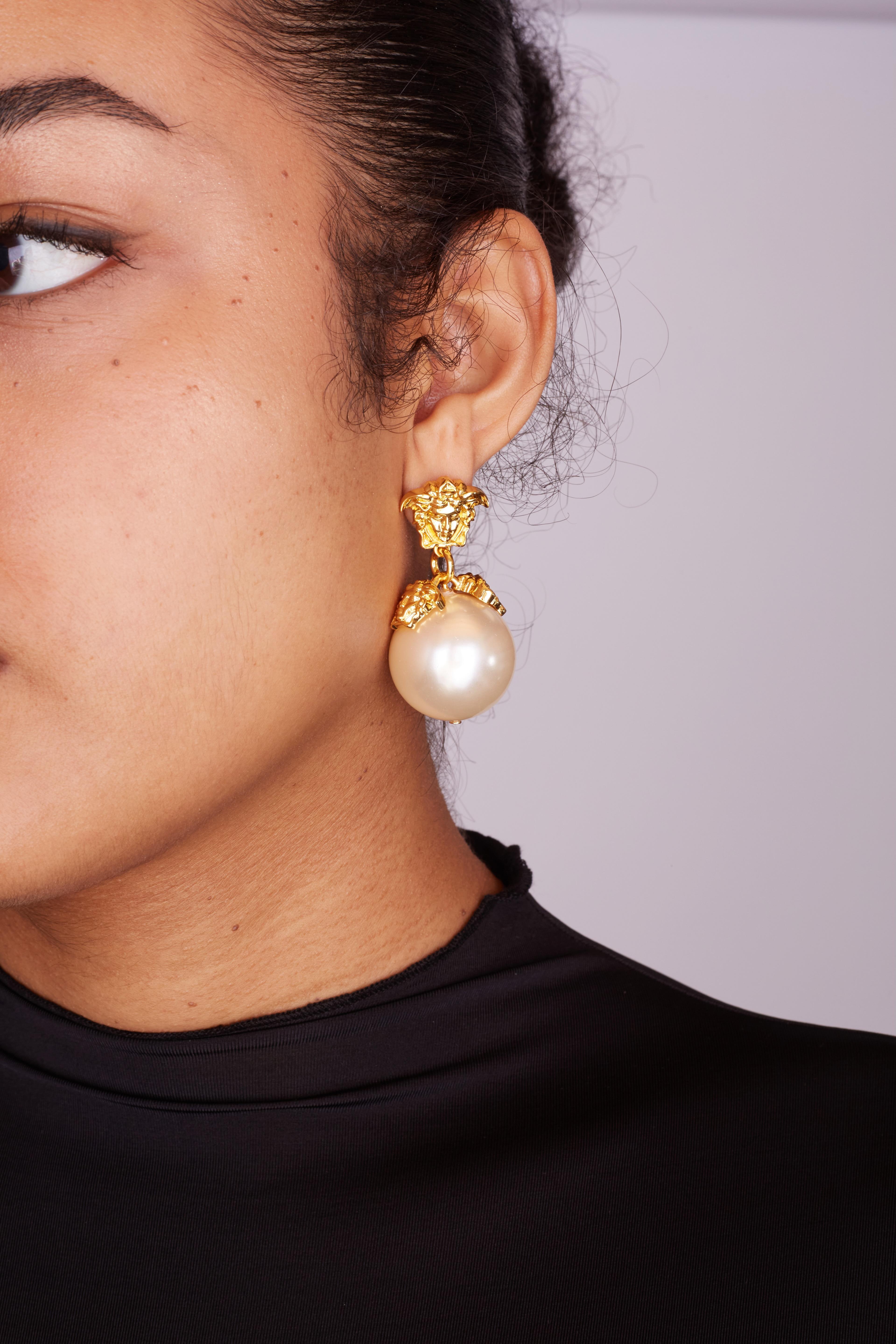 VERSACE MEDUSA FAUX PEARL DROP EARRINGS METALLIC

These classic Versace earrings are made of faux pearls with gold tone metal They feature the brands signature medusa at top with a dangling lush white pearl. For pierced ears.

Color: Gold tone and