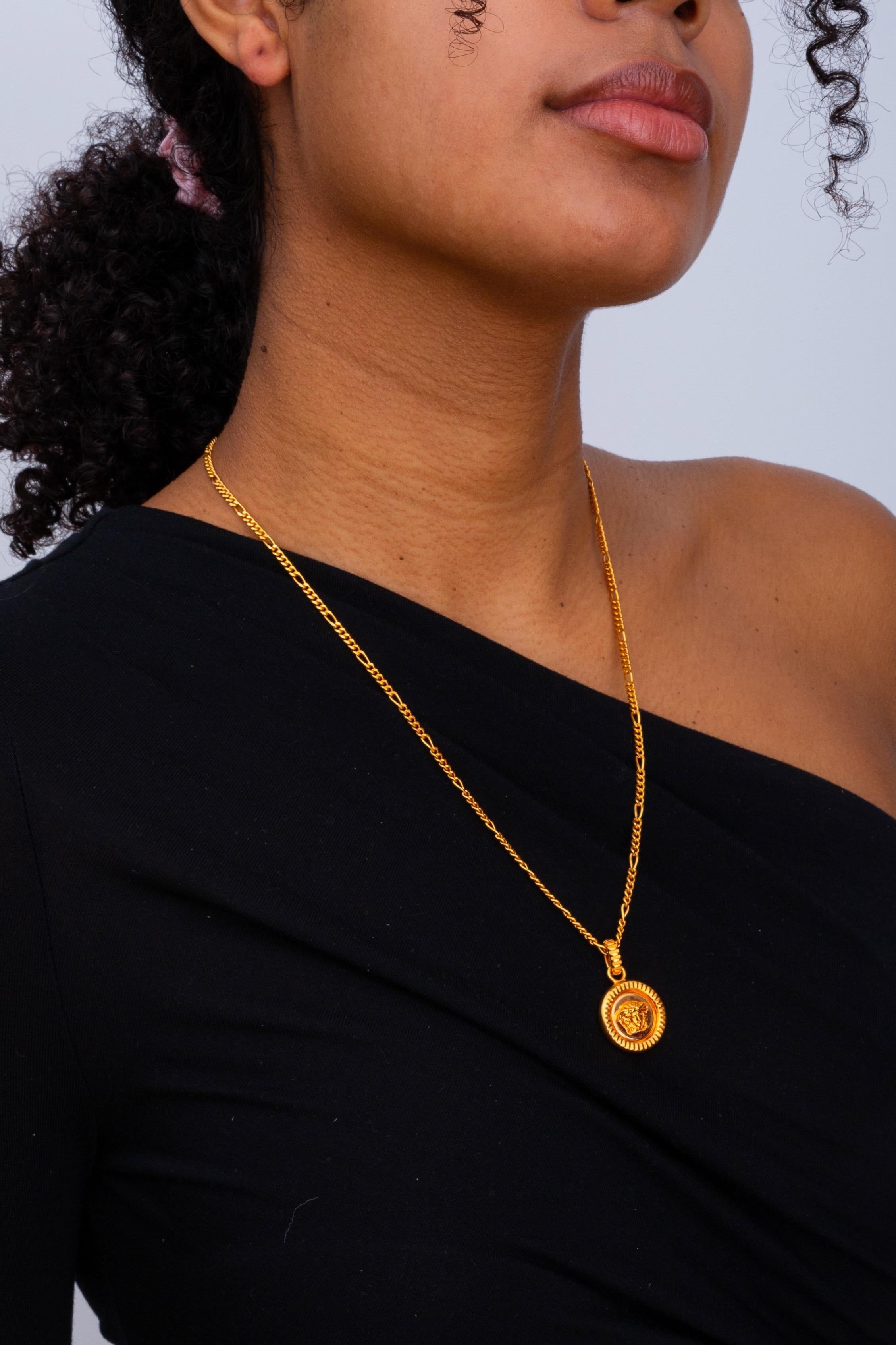 Curb chain necklace in gold-tone. Circular pendant featuring signature Medusa graphic at drop. Signature Medusa at adjustable lobster clasp fastening. Approx. 10