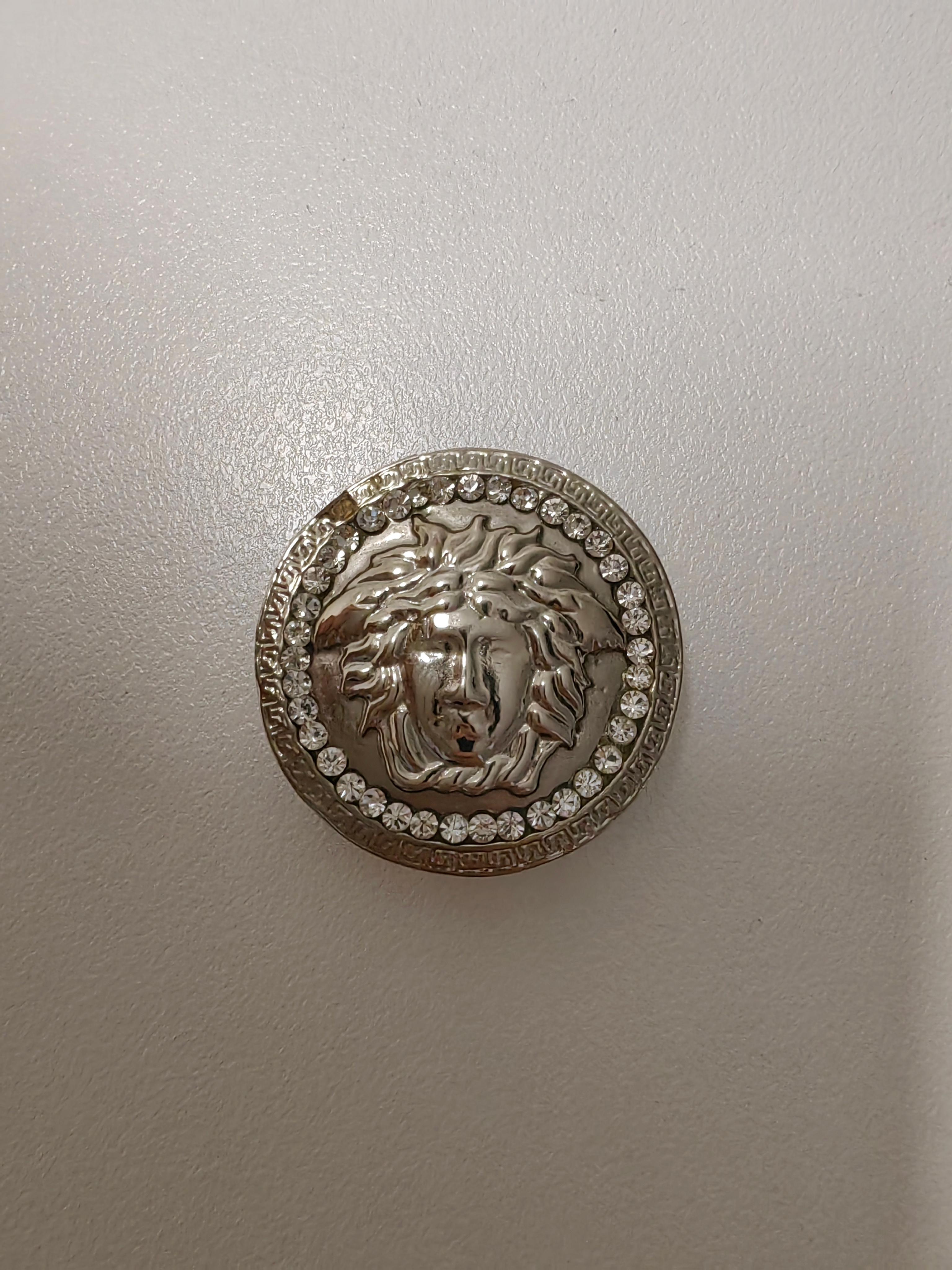 The Versace Medusa Metal Coin is an iconic and luxurious piece that effortlessly embodies the bold and opulent style the brand is known for. Crafted from high-quality metal, this Medusa coin features a striking design with rounded edges embellished