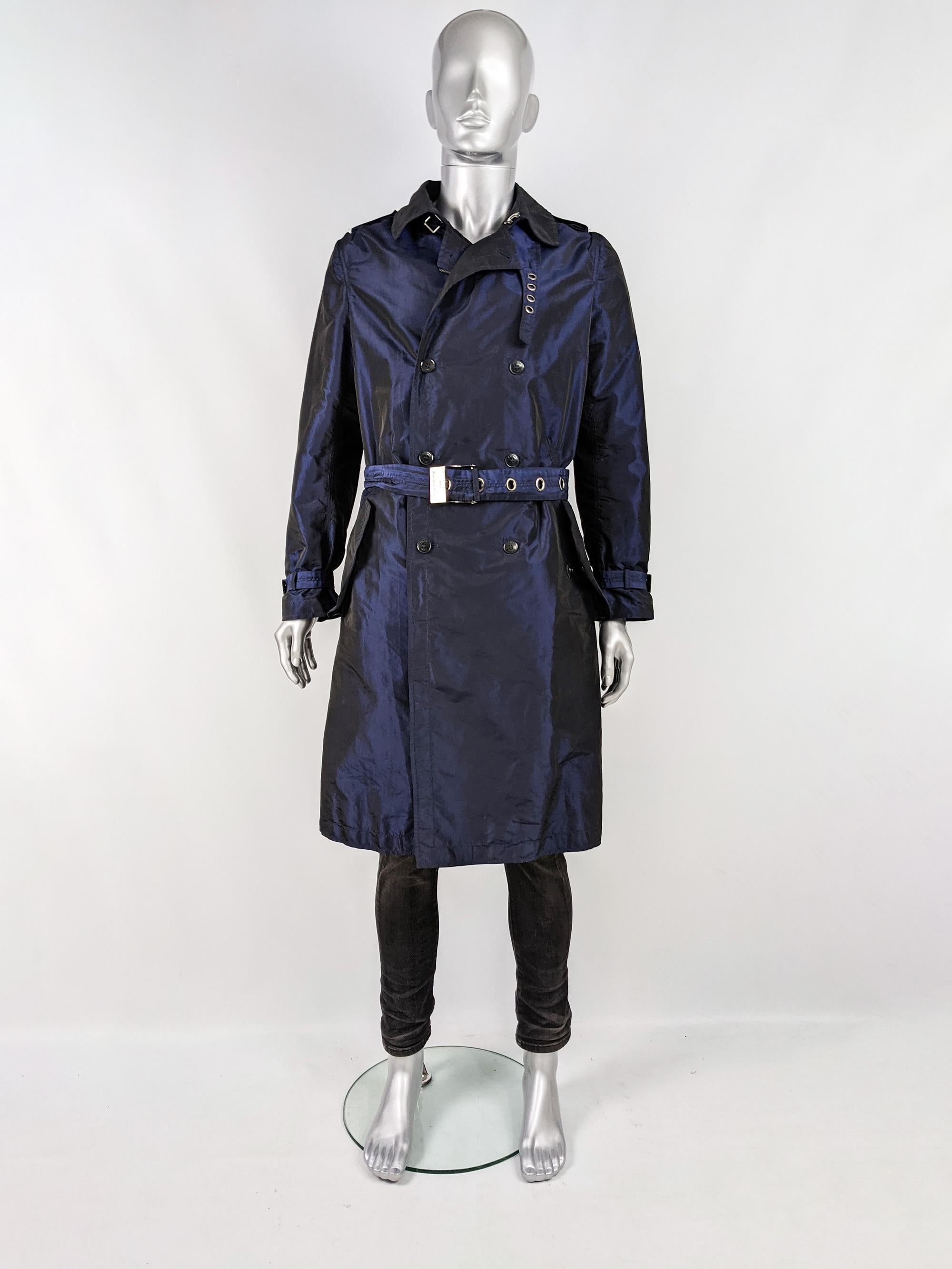 An incredible mens Versace trenchcoat in a blue iridescent taffeta fabric with amazing details like the large Versace engraved belt buckle (that can also be tied in the back), the collar strap details, leather tab to the back and concealed zip