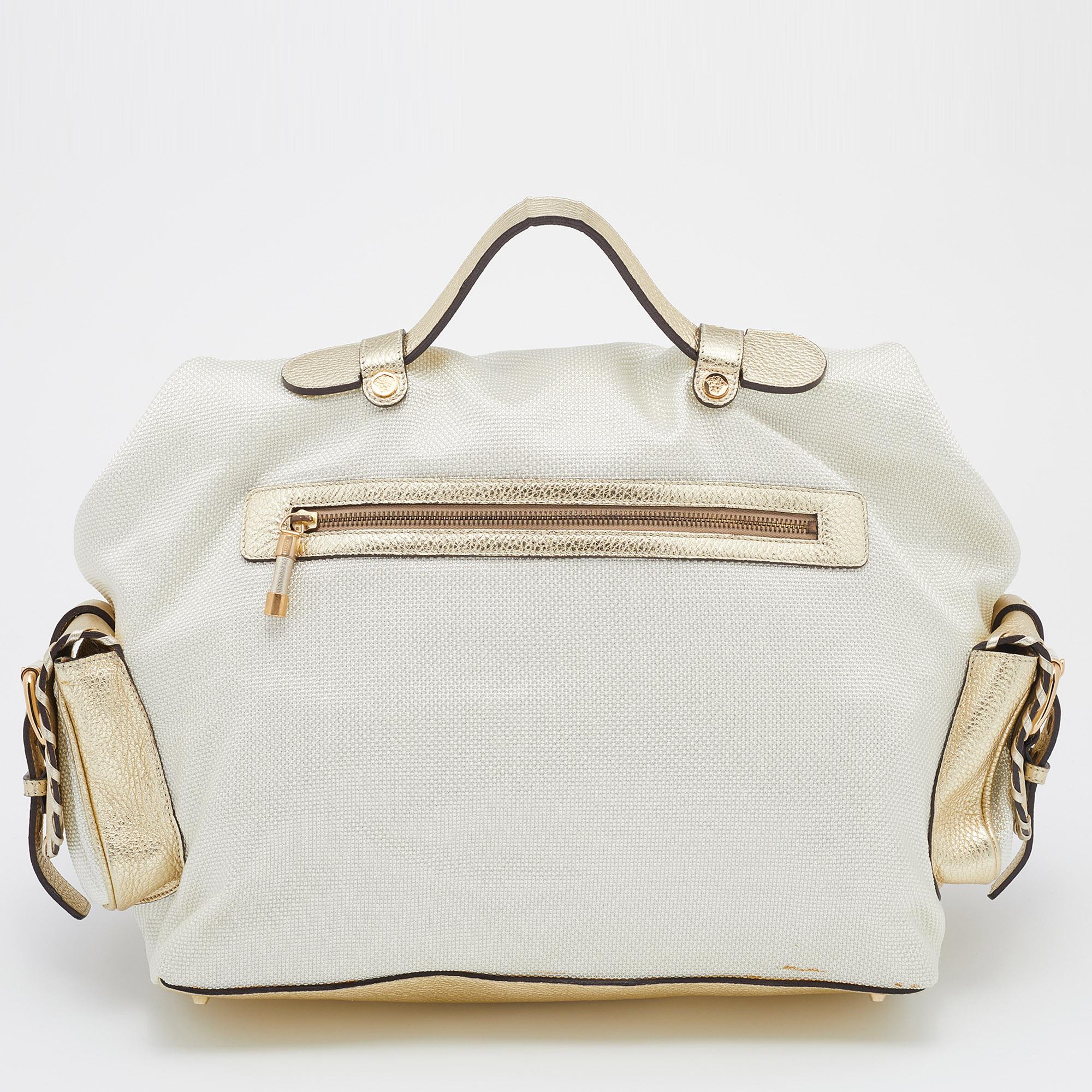 This gorgeous satchel comes from the House of Versace. It is crafted from metallic light-beige and gold leather and technical fabric on the exterior. It features two handles, gold-toned hardware, and a satin-lined interior. This stunning Versace
