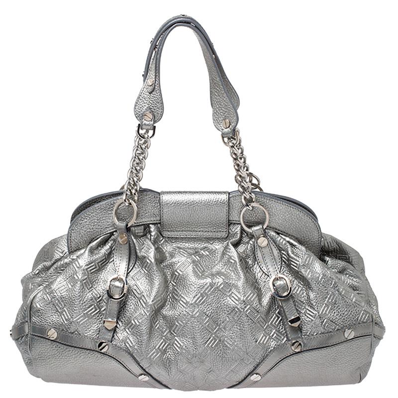 Designed in a unique and wonderful silhouette, this satchel from Versace will be a special addition for any closet. It is crafted from metallic silver leather and is accented with studs on the exterior along with a flap pocket at the front. The bag