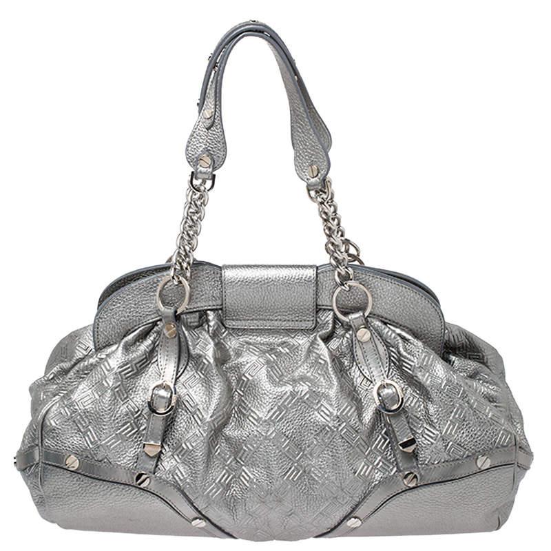 Designed in a unique and wonderful silhouette, this satchel from Versace will be a special addition to any closet. It is crafted from metallic silver leather and is accented with studs on the exterior along with a flap pocket at the front. The bag