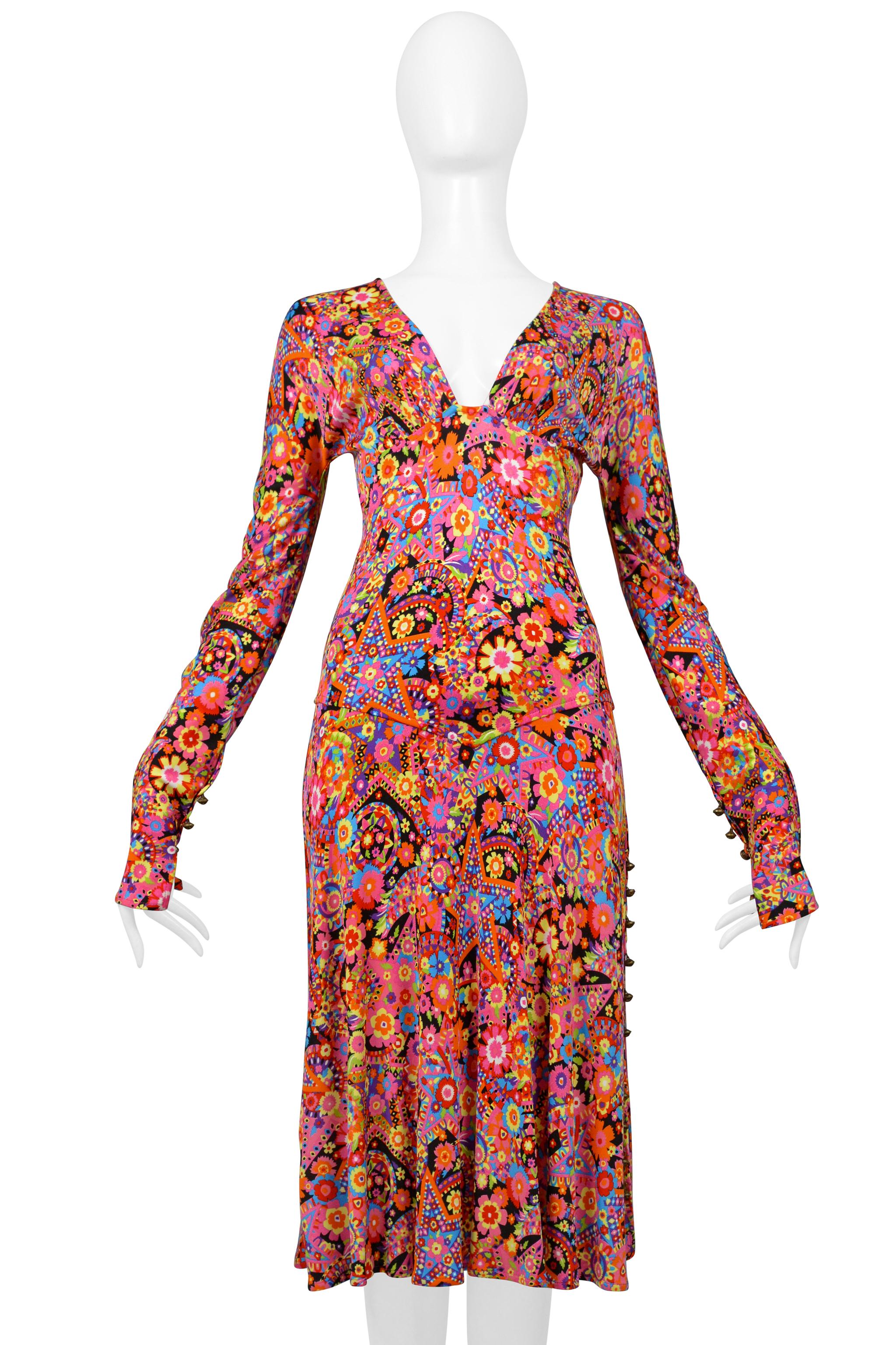 Resurrection Vintage is delighted to offer a vintage 2002 Versace dress featuring a 70s-inspired multicolor floral print, fitted long sleeves with slit cuffs and antique bronze buttons, a slit halfway up the right leg with antique bronze buttons, a
