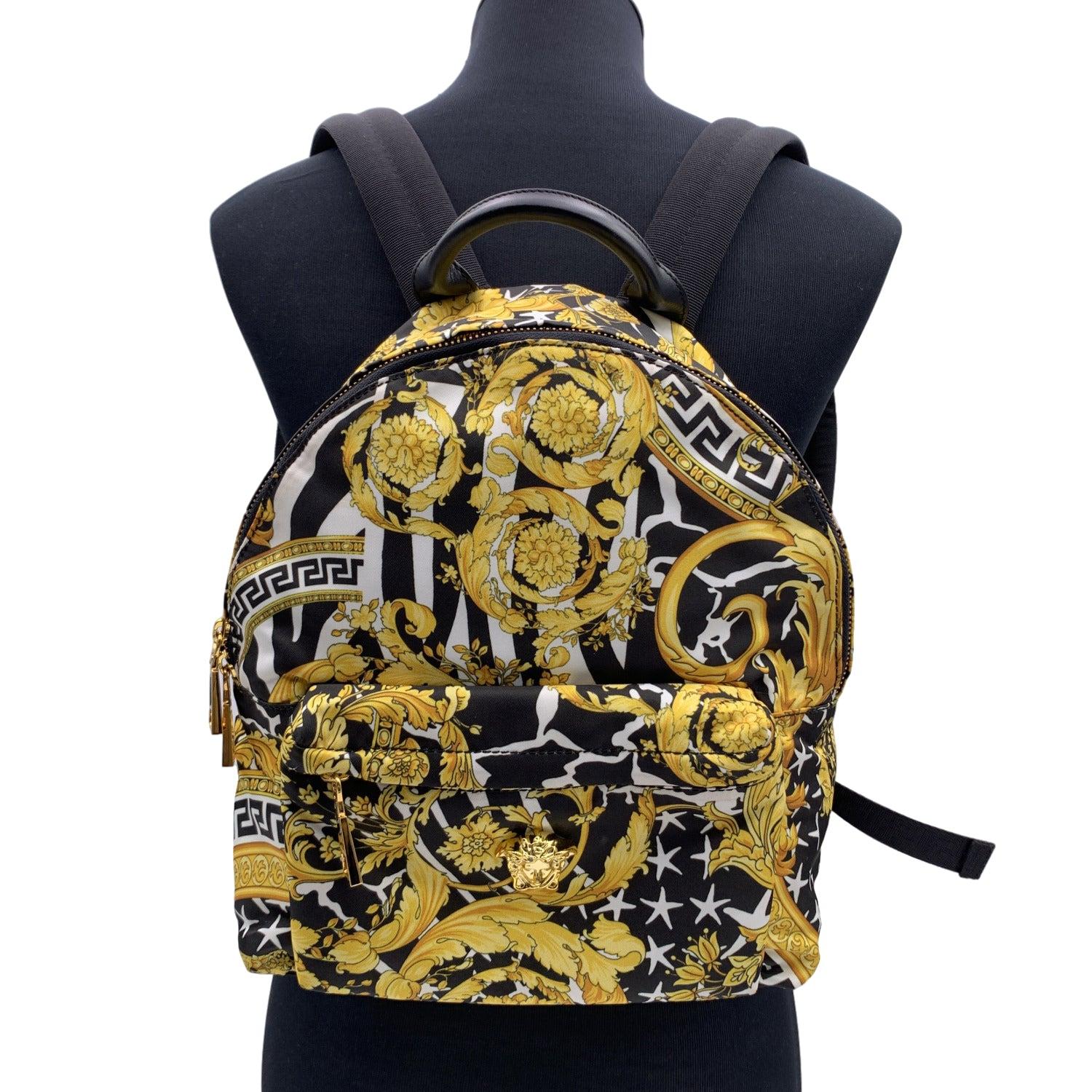 Baroque backpack by Versace. It features the iconic baroque print, a gold metal Medusa head on the front, adjustable shoulder straps, zip front exterior pocket, and a main compartment with zip fastening. Black fabric lining. 1 side zip pocket