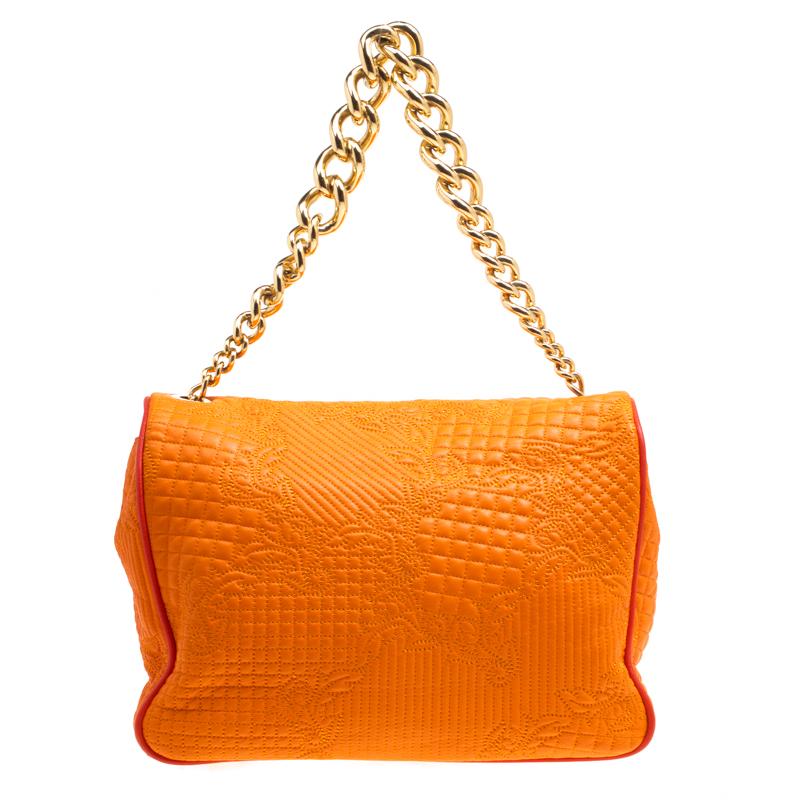 Versace brings you this glamorous Micro Vanitas bag to make you outshine everyone else and receive never ending compliments! The vibrant orange bag is crafted from leather and styled with a quilted floral design pattern on the exterior. It flaunts a