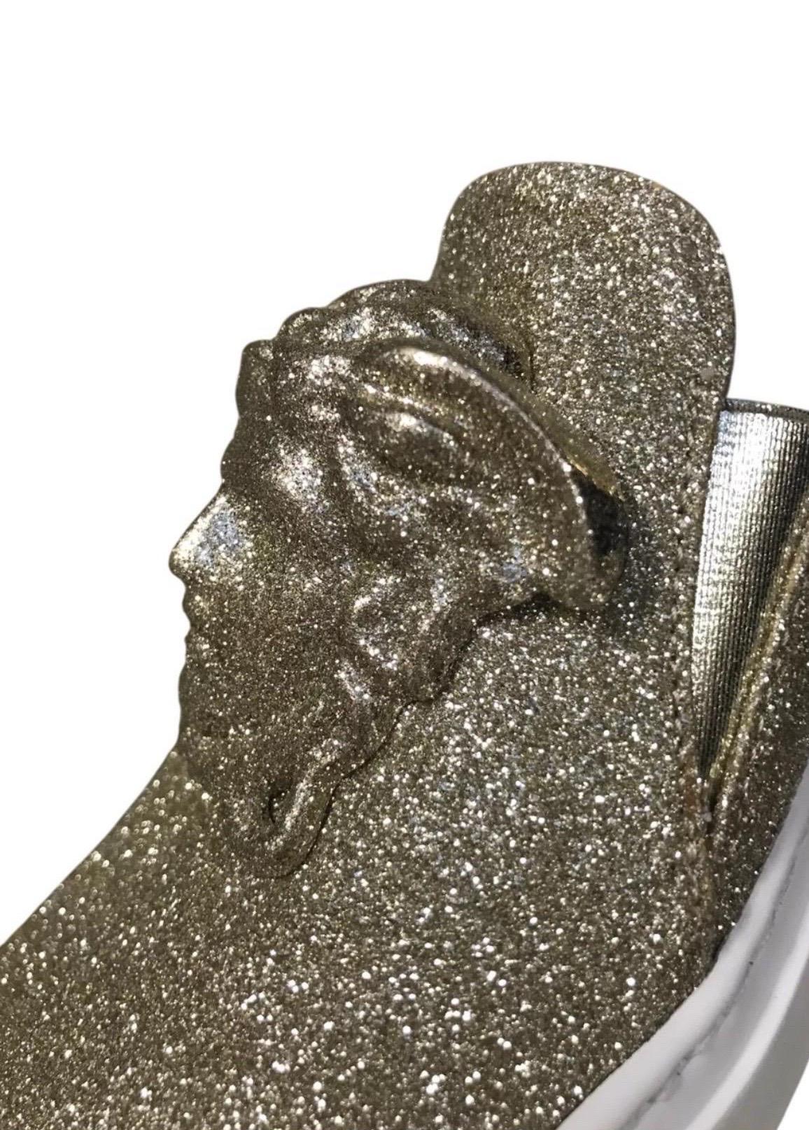 New Versace Palazzo Low-Top Sneakers in Gold Glitter

Unworn and eye-catching, these glamorous Versace slip-on sneakers feature allover gold glitter and the iconic 3D Medusa emblem at the front. The white sole balances sparkle with streetwear ease,