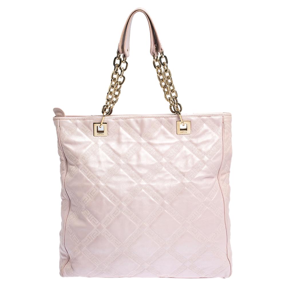 This elegant tote from Versace is crafted from pearl pink leather and is perfect for daily use. The bag features double chain handles with leather rest, protective metal feet, and gold-tone hardware. The nylon interior is spacious enough to hold all
