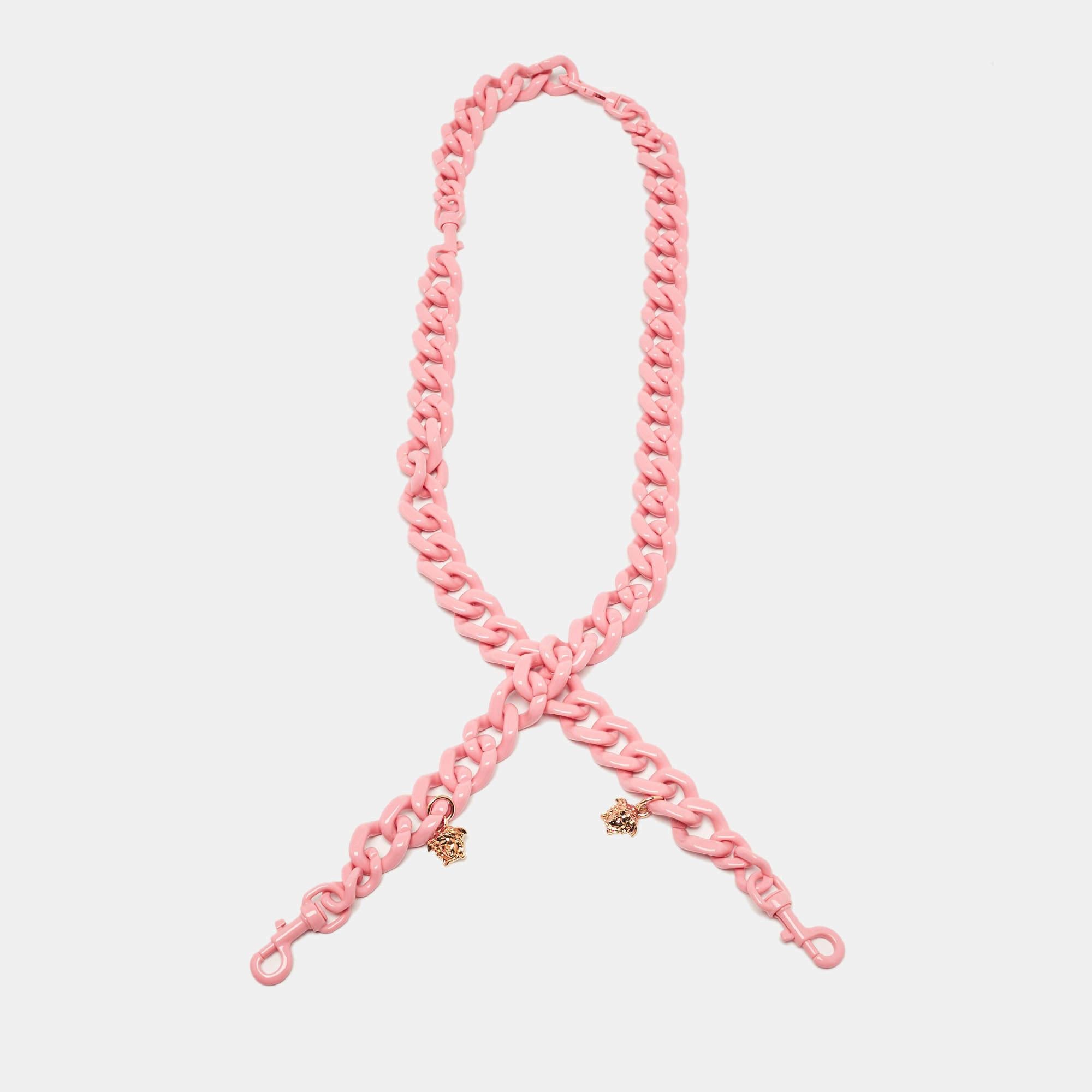 Questa tracolla Versace aggiunge un tocco audace a qualsiasi borsa. Realizzato in plastica rosa di alta qualità  il cinturino è caratterizzato da catene a maglie grosse che mettono in mostra lo stile iconico di Versace. È versatile e perfetto per