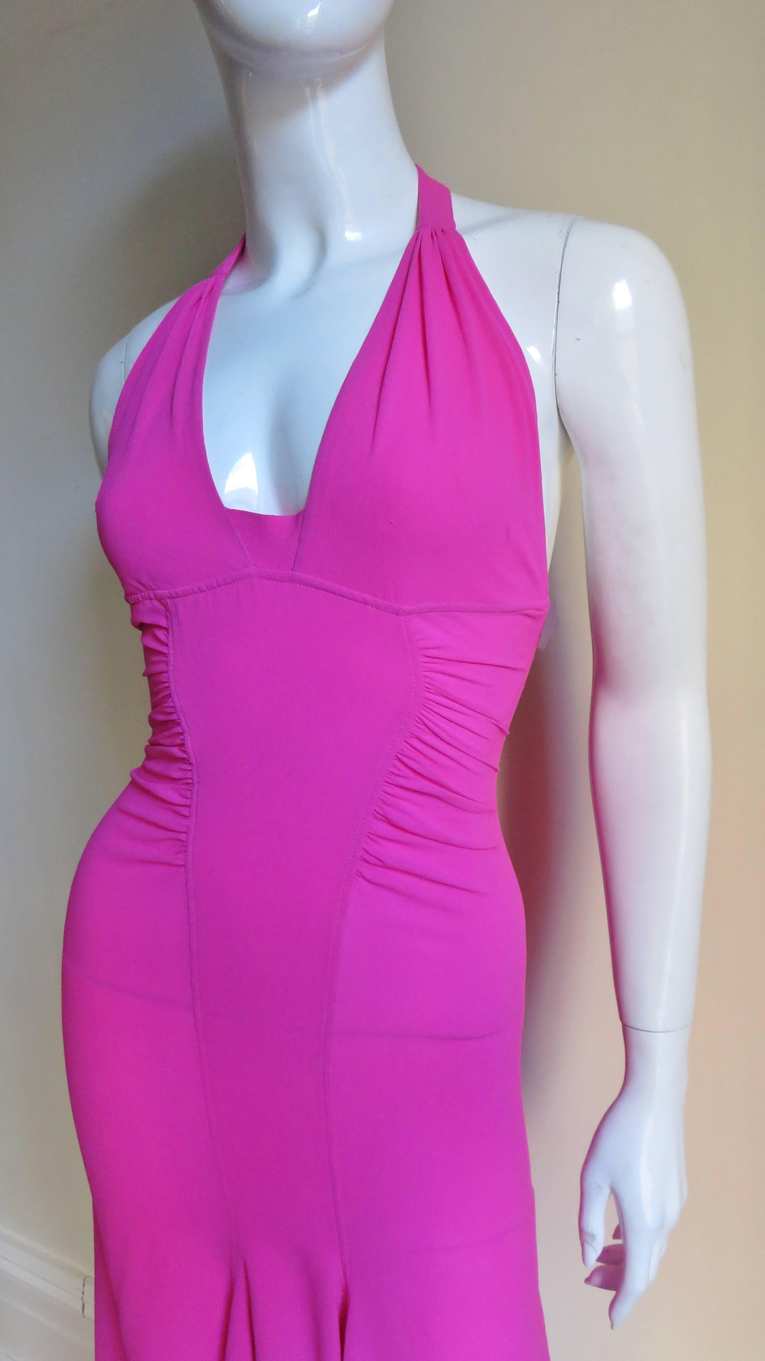 A fabulous bight pink silk dress from Versace.  It has a halter neckline, ruched side waist and the skirt flares at the hem and is slightly longer in the back. The back waist has incredible detail with 4 silver metal adjustable, functional buckles