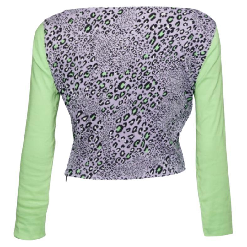 Este crop top de la Casa Versace está aquí para que vayas a la moda. Está confeccionado con tejido de punto morado, que se realza con estampados de leopardo. Presenta un corte recortado y mangas largas. Ponte este top Versace con pantalones de