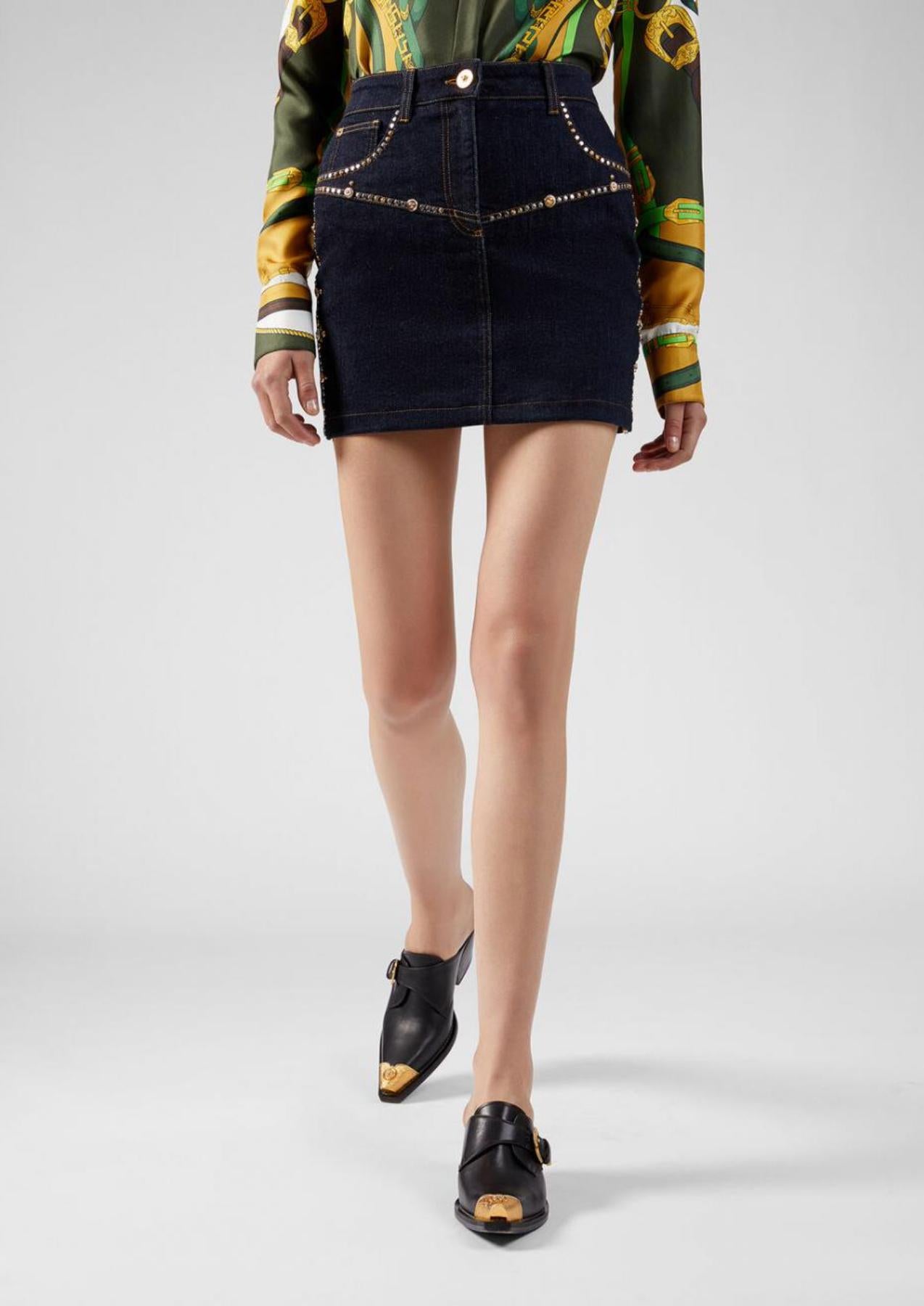 This Versace Resort 2020 jean mini skirt features dark blue denim, gold-tone stud embellishments, front button fastening, front pockets, one branded rear pocket, and a rear logo patch. Pair it with the matching Gianna signature studded jacket for