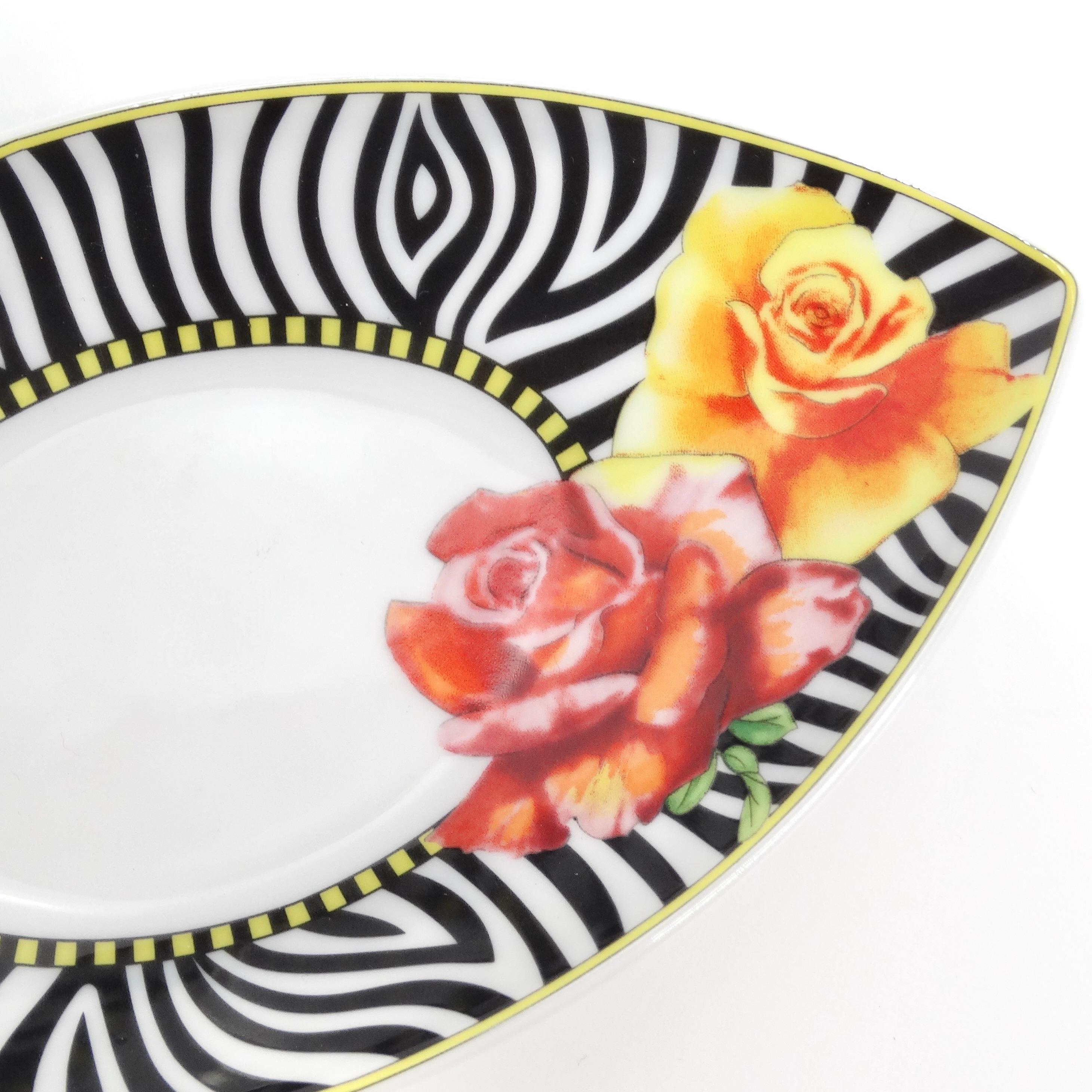 Introducing the Versace Rosenthal Hot Flowers Saucer Dish, a stunning and luxurious porcelain small oval tray designed to infuse your space with opulence and style. Crafted with meticulous attention to detail, this dish features a whimsical print