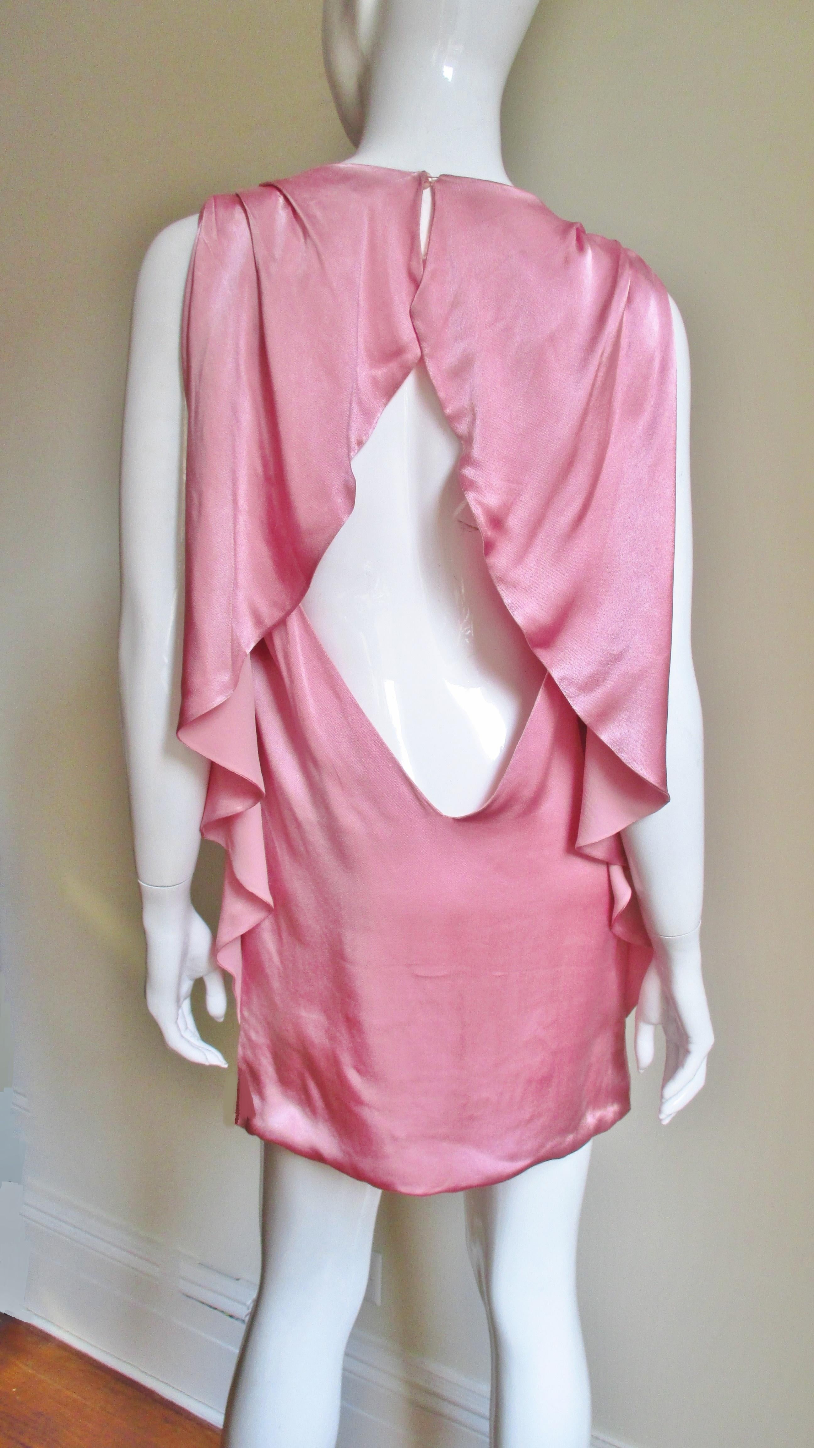 A great dress in pink crepe back silk from Versace.  It is is a simple sleeveless shift from the front.  The back is exposed from the shoulders to low back with the exception of ruffles which frame it across the shoulders and along the sides.   The