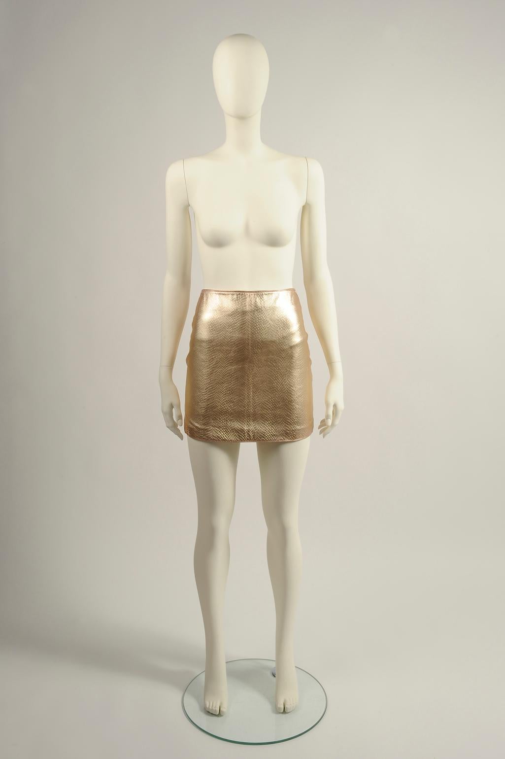 Part of the look n° 58 of the Versace 1994 Fall-Winter collection, this mini skirt is made from gold leather that has a tactile lizard-effect finish (see pictures 7 & 8). Labeled an Italian size 38 (US 0), it is fully lined in rayon that ensures a