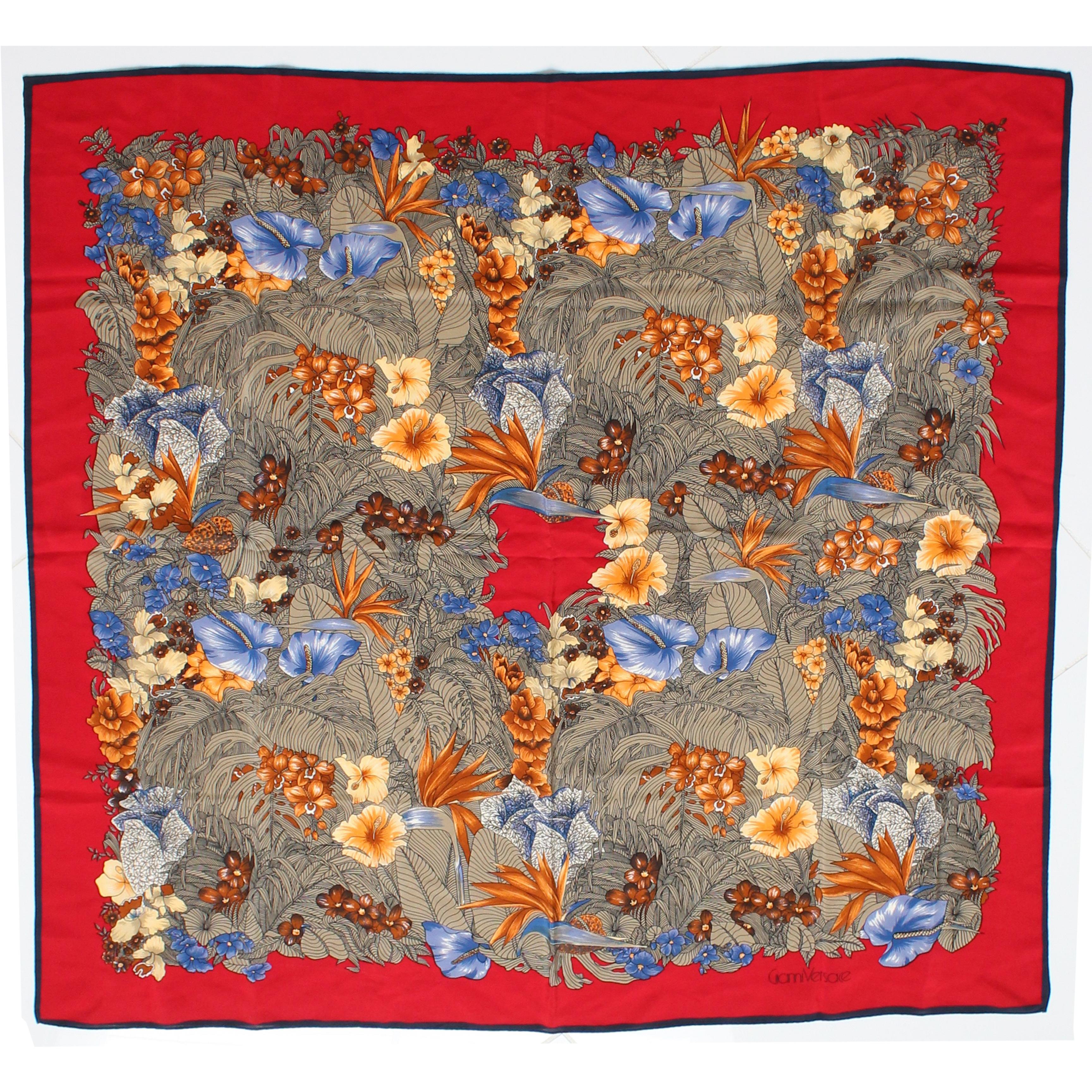 This colorful silk scarf or shawl was made by Gianni Versace, most likely in the early 90s. Made from silk, it features a beautiful red border with a stunning graphic floral print throughout.   At 35in square, it can be worn several ways and the