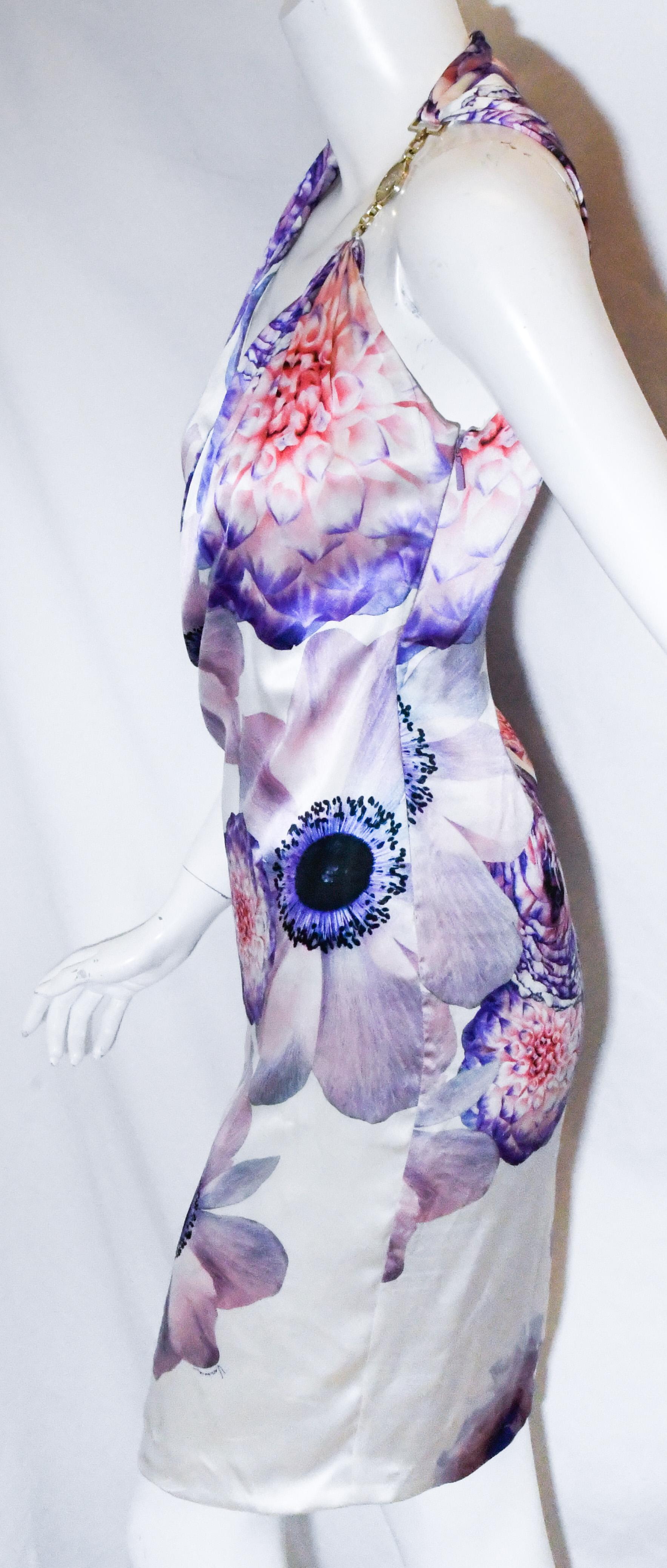 Versace halter dress composed of silk fabric with white base and large purple flowers.  This dress can be worn for a daytime lunch or an evening affair.   The top of this dress has a wrap effect creating a deep V neck decolletage in this sexy,
