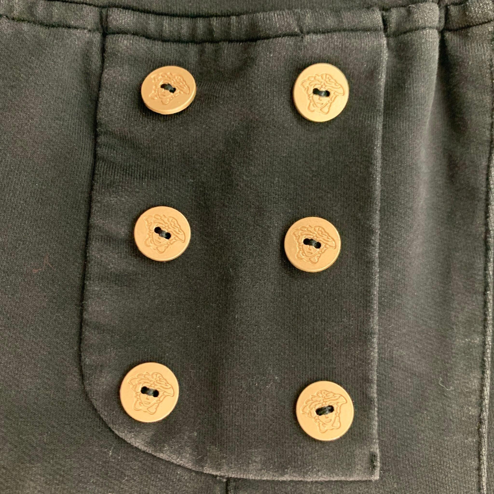 VERSACE shorts comes in a black cotton jersey knit material featuring medusa gold buttons detail, drawstring and an elastic waist. Very Good Pre-Owned Condition. Moderate color fading. 

Marked:   L 

Measurements: 
  Waist: 27 inches Rise: 8.5