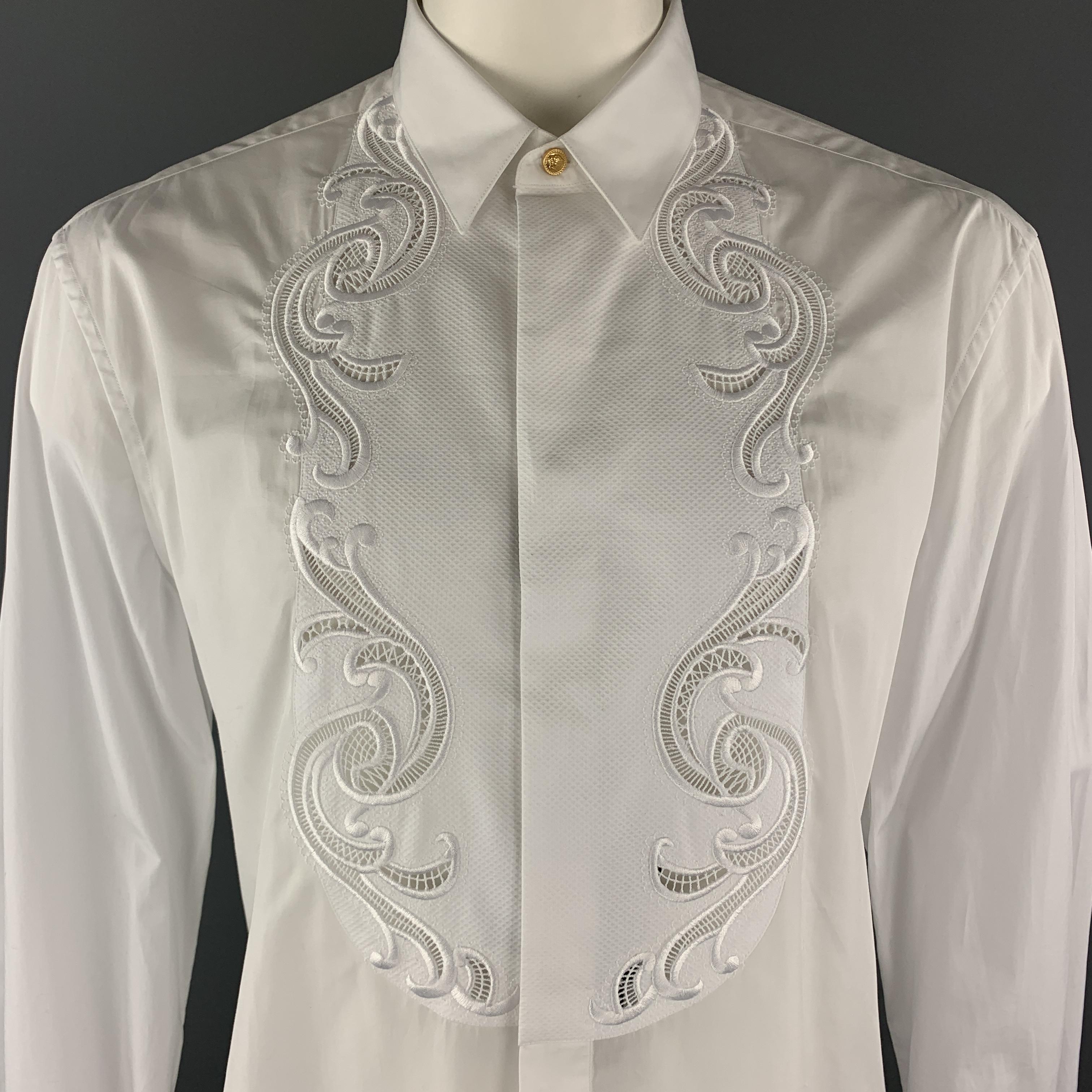 VERSACE dress shirt comes in white cotton poplin with a pointed gold tone Medusa button collar, hidden placket button front, link cuffs, and textured bib with Baroque lace cutout trim. Made in Italy.

Brand New.
Marked: US
