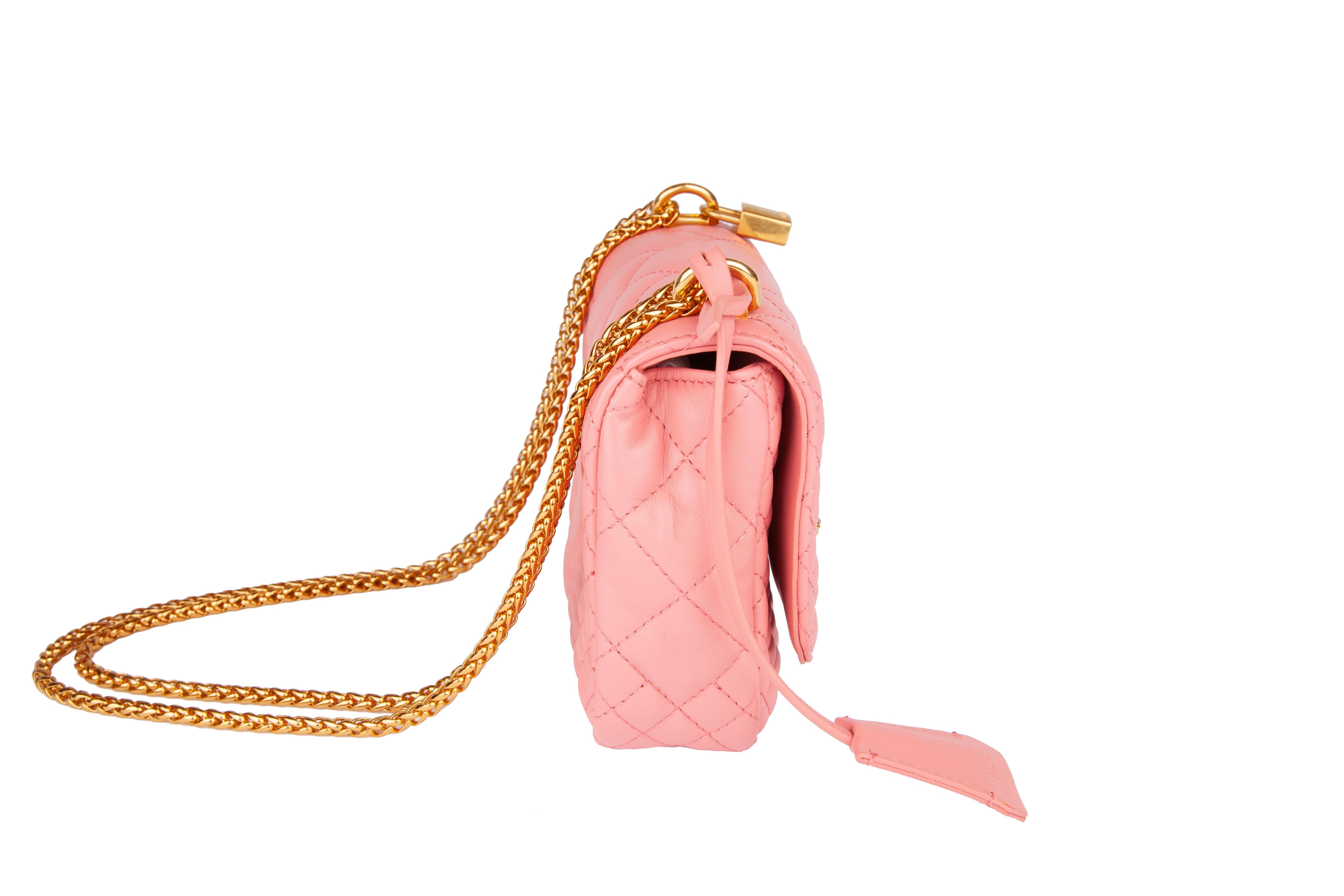 This Versace small shell pink icon shoulder bag features quilted calf leather, gold tone chain and hardware, a flap with medusa studs, a twist clasp, and one main compartment with a slip pocket. The small icon shoulder bag is both functional and