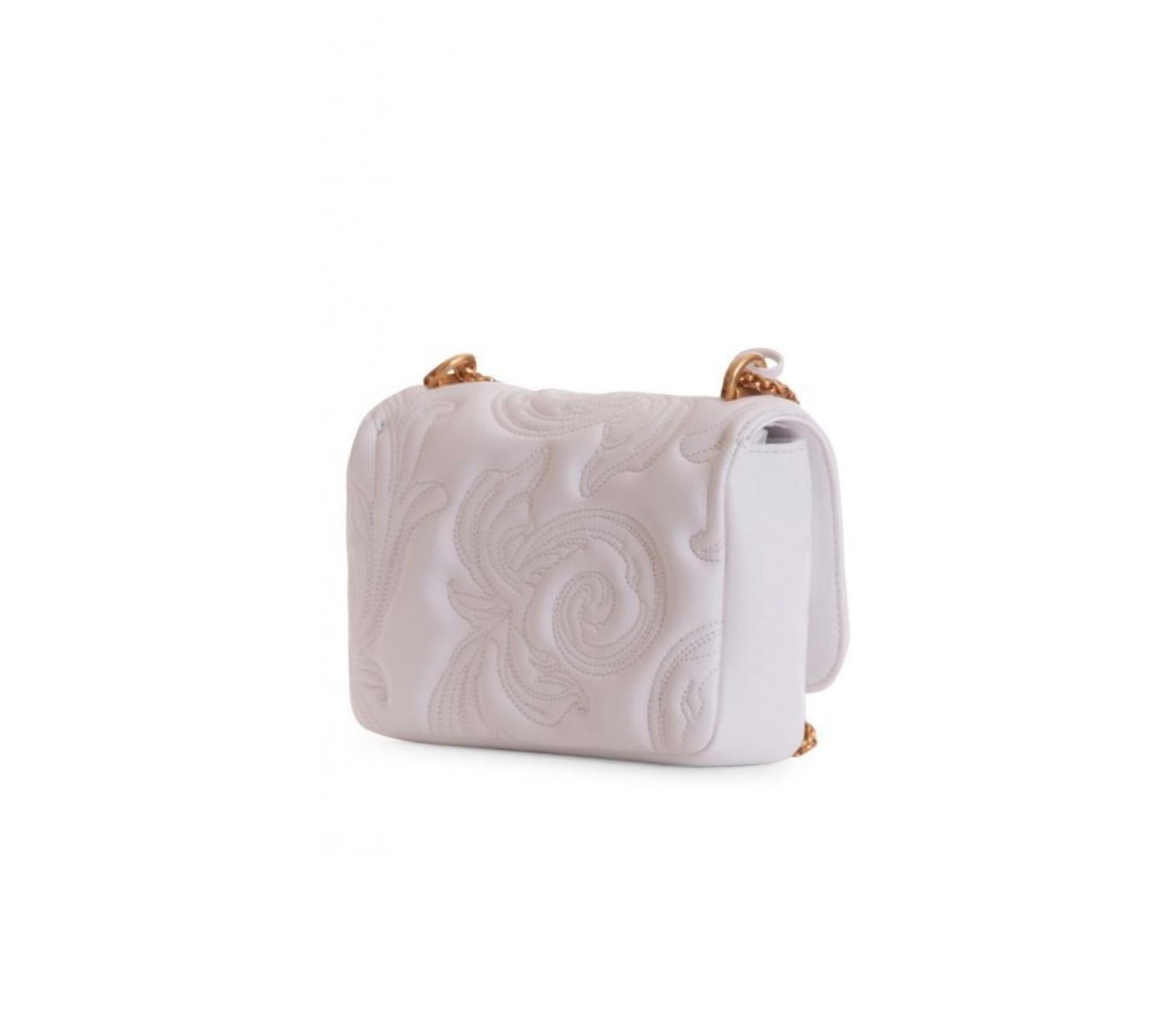 This small Versace white icon shoulder bag features a Barocco embroidery, gold tone hardware and chain, a flap with 2 medusa studs, a twist clasp, and one main compartment with a slip pocket. The small icon shoulder bag is both functional and