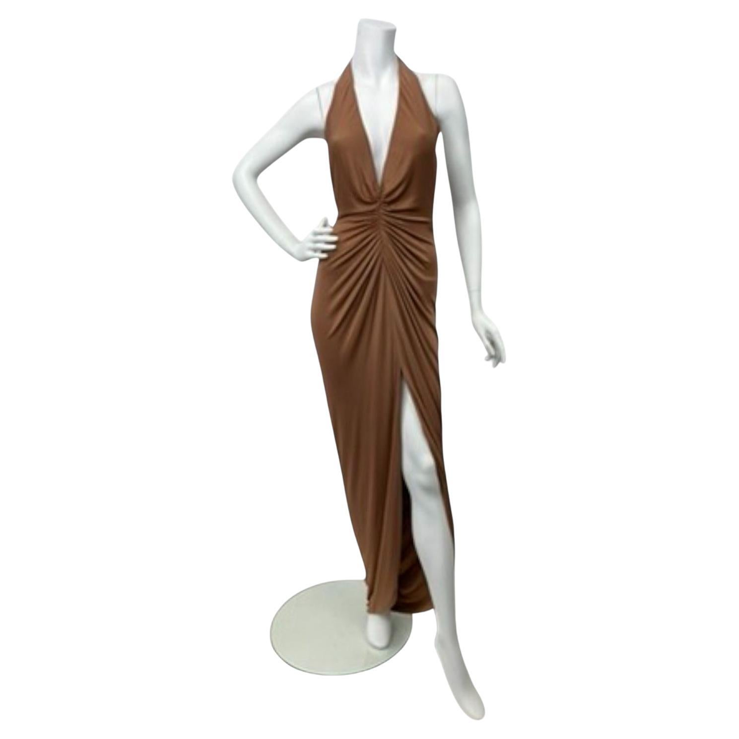 Este vestido, una pieza espectacular del Look 49 de la colección de pasarela Primavera/Verano 2005 de Versace, encarna la mezcla de glamour y sensualidad característica de la casa. Confeccionado en seda fluida, el diseño presenta un escote