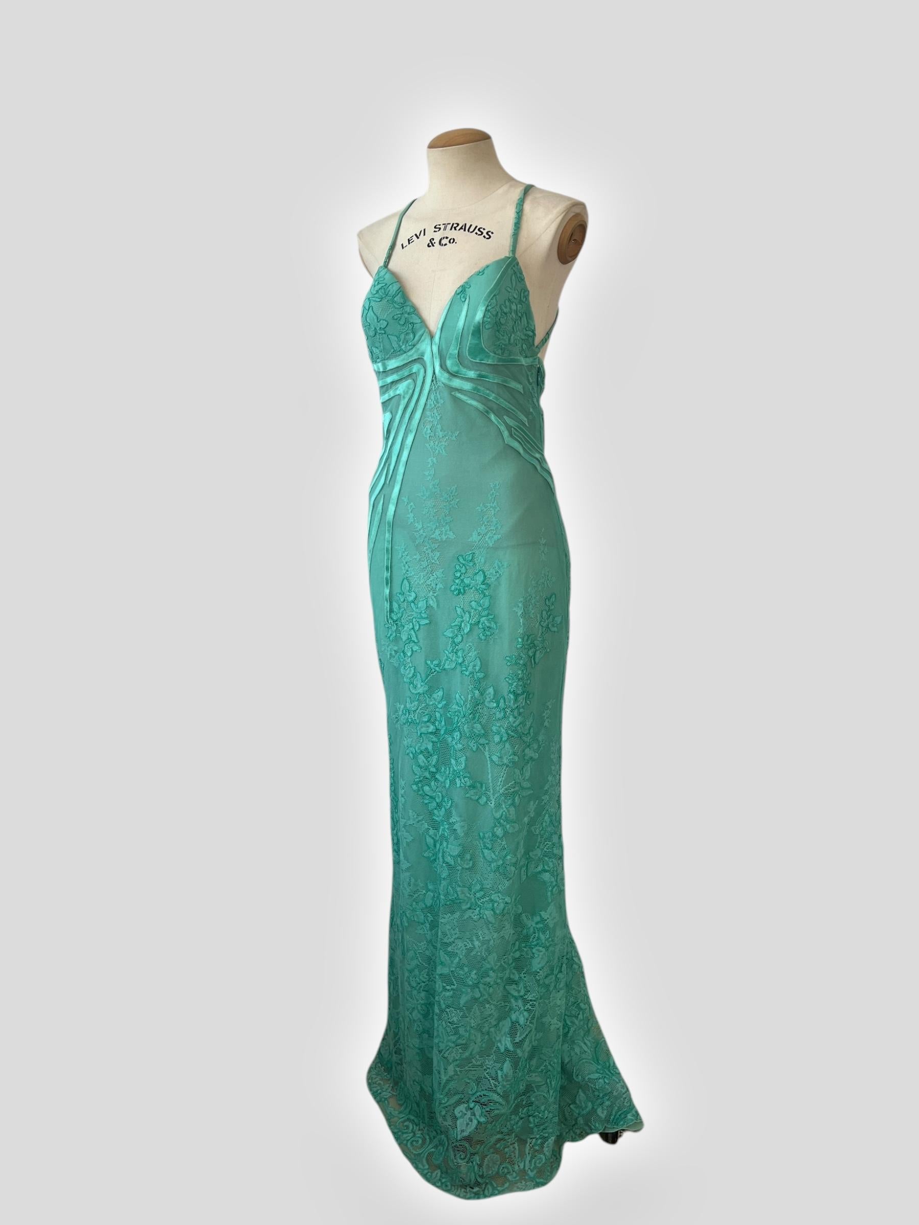 An ethereal vintage Versace gown from the Spring/Summer 2000 collection, featuring a stunning seafoam green lace overlay with intricate satin appliqué detailing. The sheer mesh bodice is accentuated with delicate crisscross straps at the back,