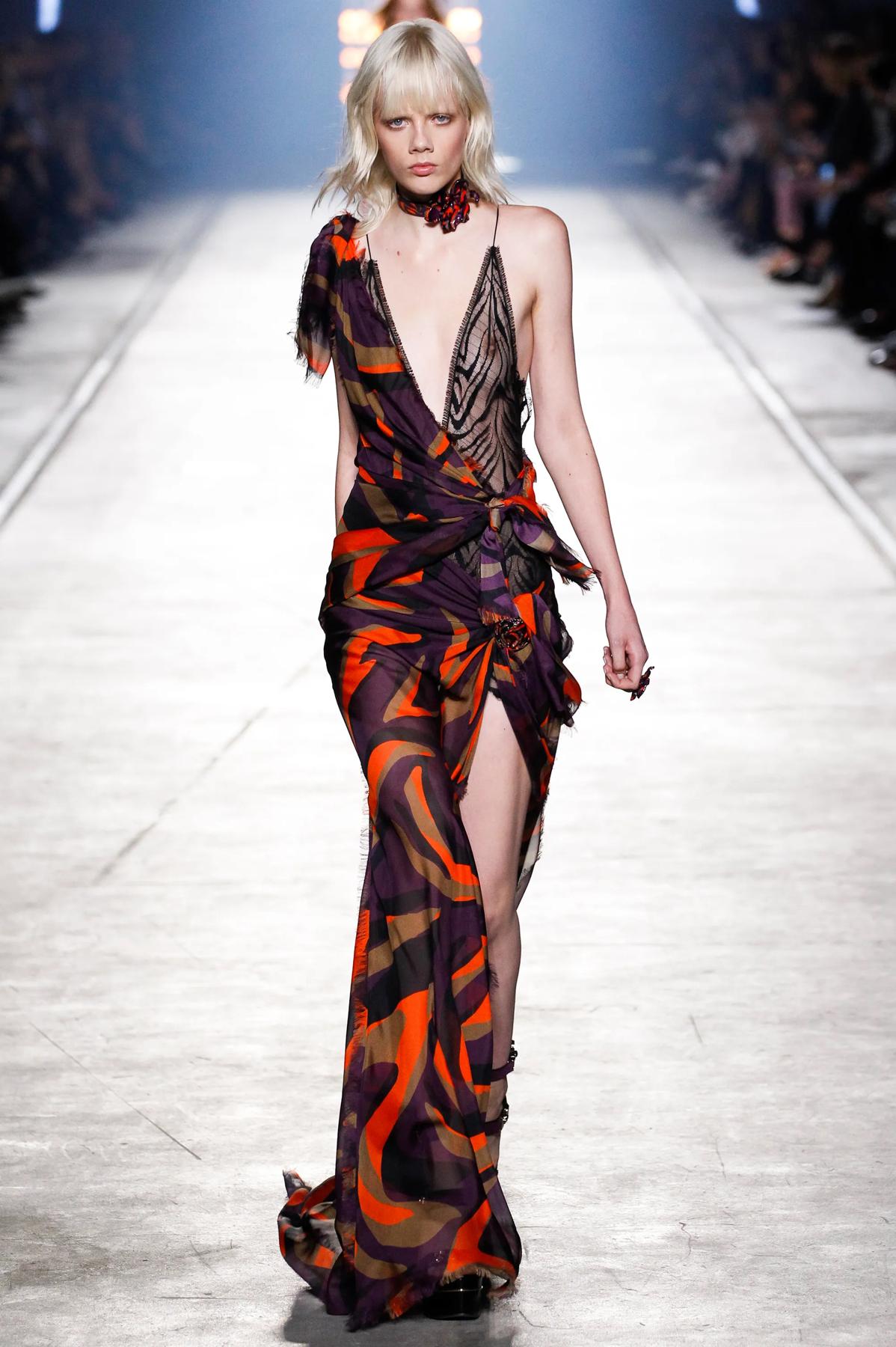 Como se vio en la pasarela de primavera de 2016, este impresionante vestido de seda tiene un profundo escote, una larga cola vaporosa, una enagua negra y un estampado naranja, morado y marrón. Kendall Jenner estaba guapísima con este vestido en la