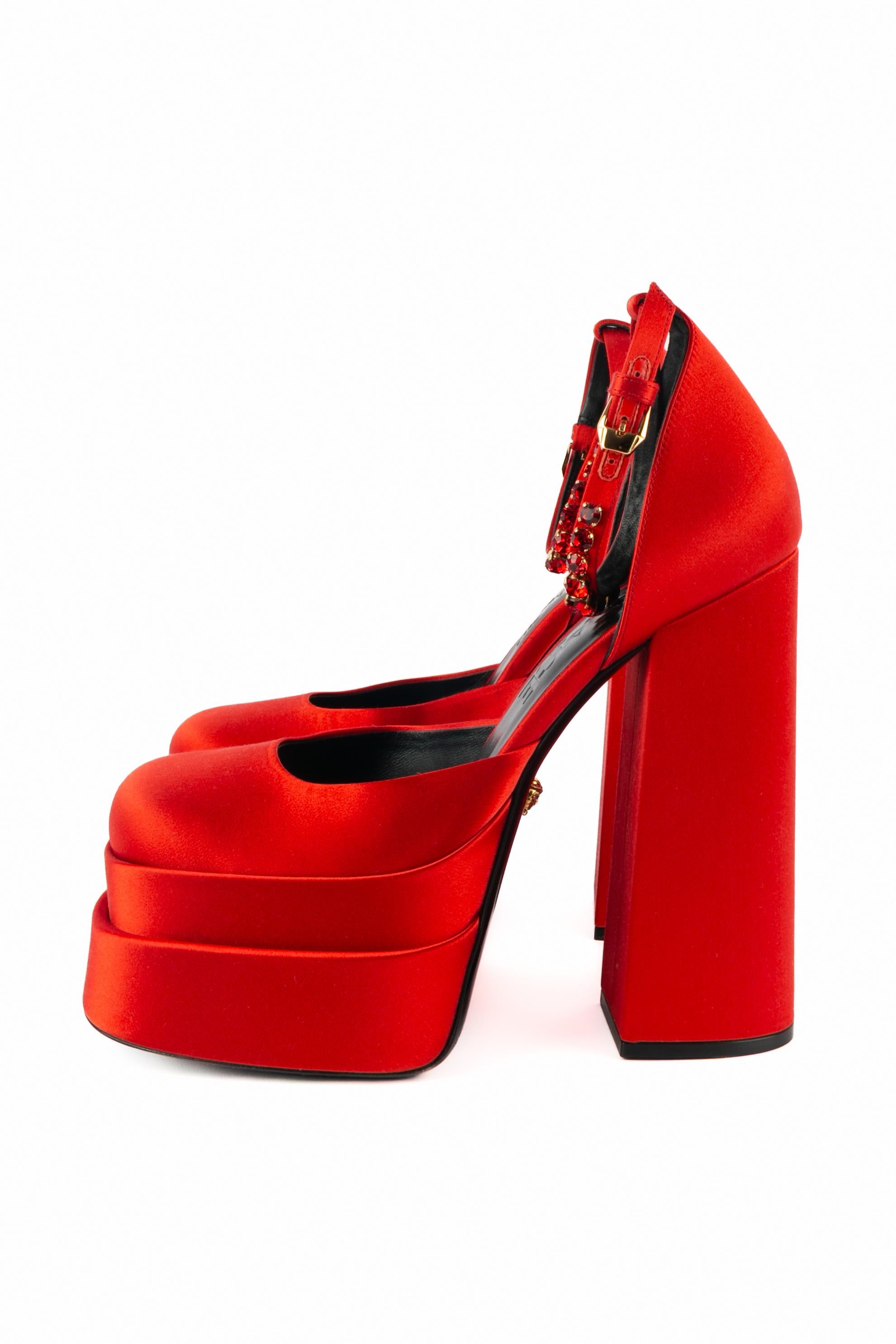 VERSACE - (Made in Italy) Hochhackige Stöckelschuhe aus rotem Satin mit zweistufiger Plateausohle. Die Handgelenkszaumzeugs sind mit rosa Strasssteinen verziert und mit goldenen Metallcharms in Form von Medusen verziert. Größe 40FR angegeben. Eine