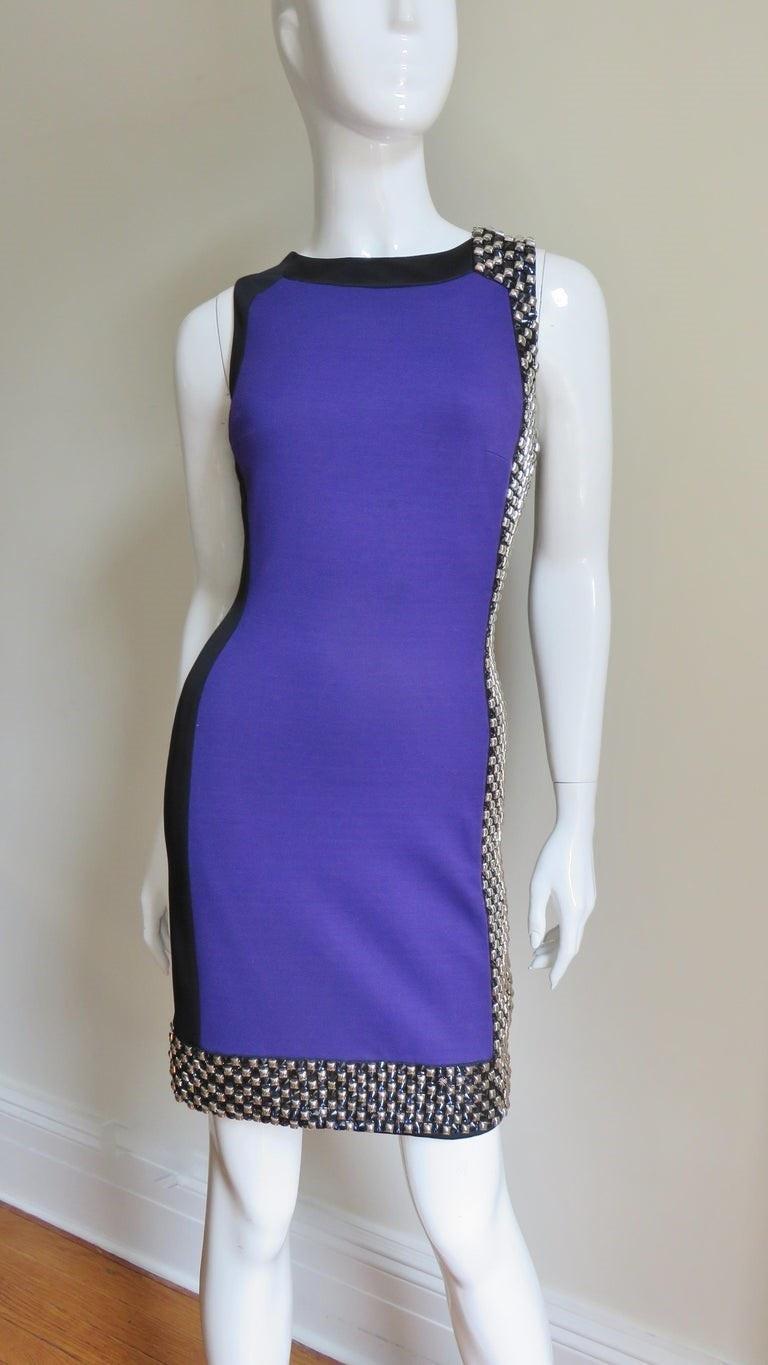 A fabulous dress from Versace in purple and black silk jersey.  It is sleeveless, semi fitted with a purple front panel and with insets of black along one side and front hem covered with extensive purple beading and silver metal studs. The back of