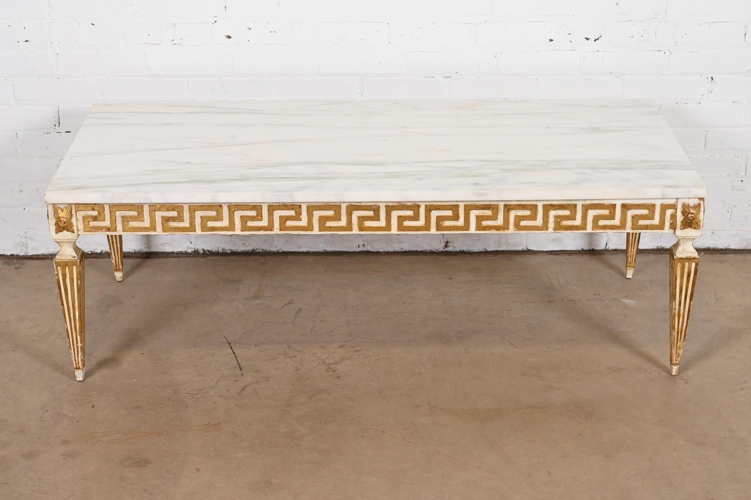 A gorgeous Neoclassical style coffee table or cocktail table

In the manner of Gianni Versace

Italy, Circa Mid-20th Century

Carved cream and gold gilt hardwood base, with Greek key design, and Carrara marble top.

Measures: 52