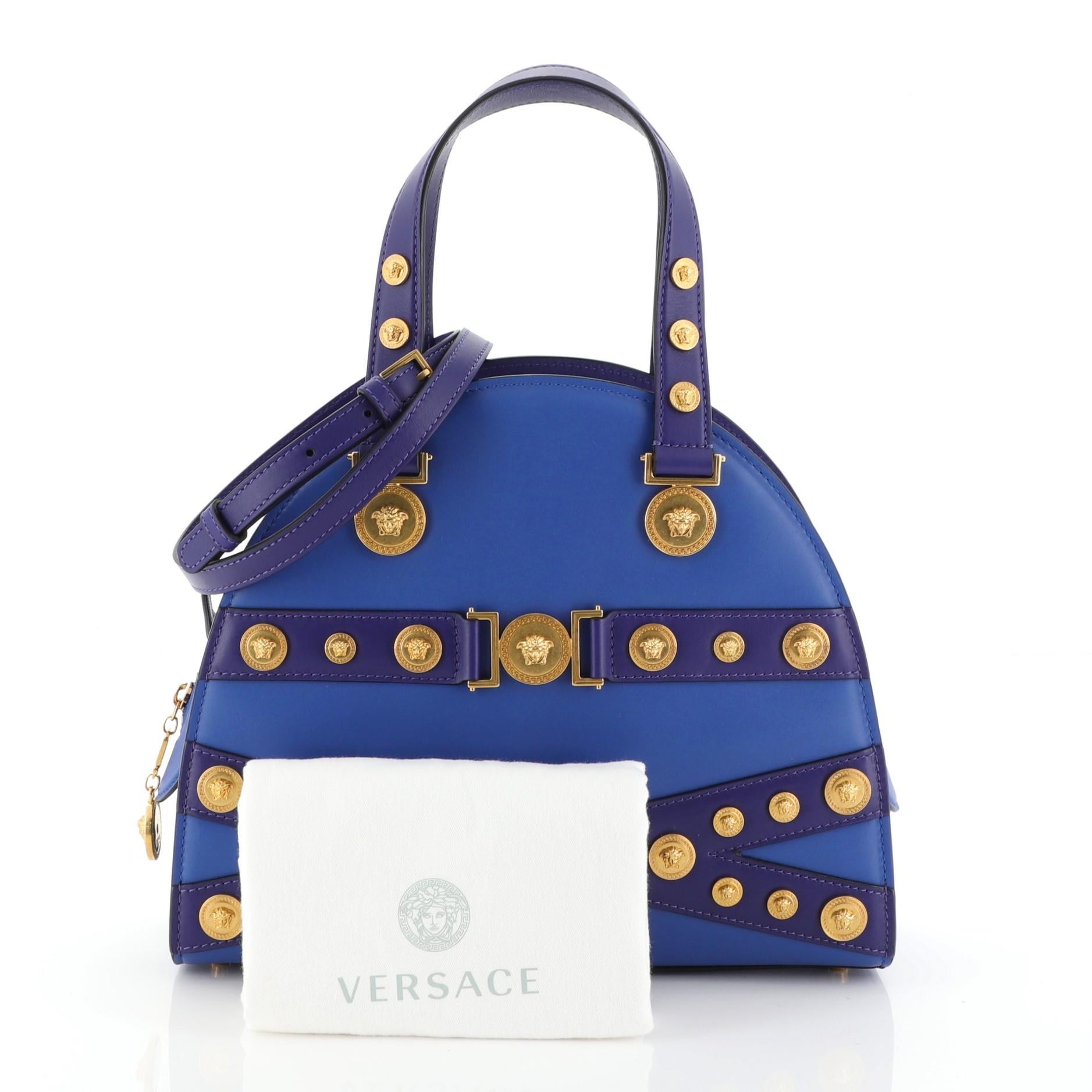 This Versace Tribute Medallion Bowling Bag Leather Medium, crafted from blue leather, features dual leather handles, medallion accents, and gold-tone hardware. Its zip closure opens to a blue leather interior. 

Condition: Excellent. Light scuffs
