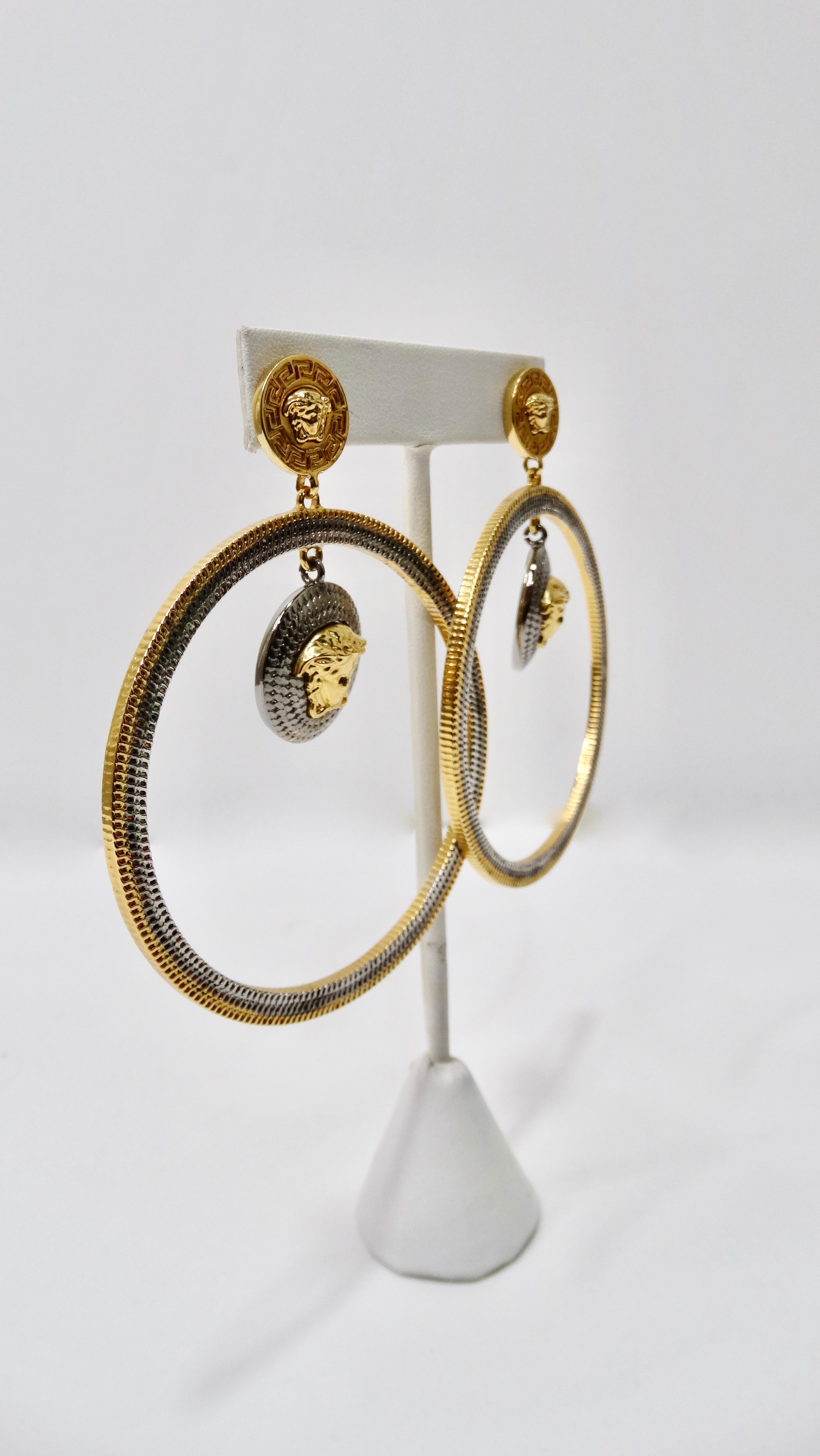 Snag yourself these hoops! Circa late 1990s, these gold and silver plated Versace hoop earrings feature a dangling medusa head pendant, a medusa head closure and the iconic greek key. Pierced backs. Pair with your favorite Versace silk shirt and