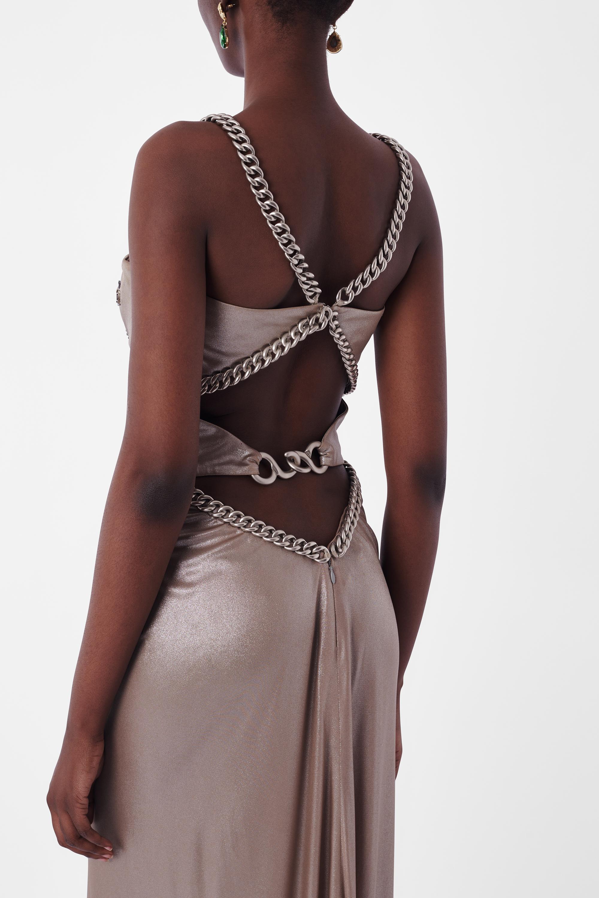 Wir freuen uns, dieses Vintage Versace 1990's Silver Metallic Chain Gown zu präsentieren. Mit silberfarbenen, gekreuzten Rückenträgern und Taillengürtel, offenem Rückenausschnitt, silberfarbenen Perlenstickereien auf der Brust und Maxilänge. In